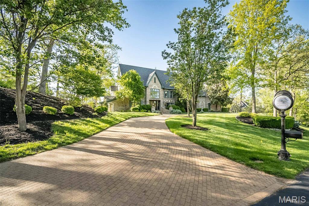 Have you been searching for a truly one-of-a-kind, custom home in the St. Louis area? From the moment you arrive, you’ll be captivated by this extraordinary, European-inspired 1.5 story estate, perfectly situated on a breathtaking 3+ acre private lot. A sweeping brick drive—designed in true Old World fashion—wraps gracefully around to a three-car rear-entry garage, setting the tone for what lies ahead. Authentic exterior lighting and architectural antique elements throughout reinforce the home’s timeless appeal.
Entering through impressive French doors, you are welcomed by a grand two-story foyer featuring a sweeping staircase and custom flooring. A richly appointed den/study showcases extensive millwork, a beamed ceiling, and custom built-in bookcases. The formal dining room is both elegant and distinctive, offering access to a private patio and a charming turret seating area—perfect for unforgettable gatherings.
The two-story great room impresses with dramatic millwork, a fireplace, and an exquisite walk-behind wet bar, ideal for entertaining. Beautiful wood floors flow throughout the main level, complemented by soaring ceilings—including two-story, nine-foot, and vaulted designs—that enhance the home’s grandeur.
The fabulous, fully customized chef’s kitchen is thoughtfully designed with granite countertops, top-of-the-line appliances, a spacious breakfast room, and an adjoining hearth room, making it the heart of the home. A large main-floor laundry room offers a utility sink, built-in cabinetry, and two utility closets for exceptional functionality.
The vaulted main-floor primary suite serves as a private retreat, featuring a spa-like ensuite bath with separate custom full-height vanities, a soaking tub, an expansive walk-in shower, designer flooring, and a large walk-in closet with an adjoining dressing area.
The upper level includes four generously sized bedrooms, two Jack & Jill baths with full-height vanities, and a large bonus room (32x17)—ideal as a recreation space, third family room, or study area.
The professionally finished walkout lower level expands the living space with a media room complete with theater screen and seating, a bathroom, fireplace with gas logs, space for a game table, an exercise room, and a large area with rough-in for a future wet bar.
Enjoy spectacular views from every rear-facing room, along with a private patio and a large deck that seamlessly connects to the driveway area—perfect for indoor-outdoor living. With three beautiful fireplaces, unrivaled craftsmanship, and a design inspired by European mansions of the past, this home masterfully blends Old World charm with today’s modern technology.
This is more than a home - it’s a custom-crafted estate designed for a growing family and exceptional living.