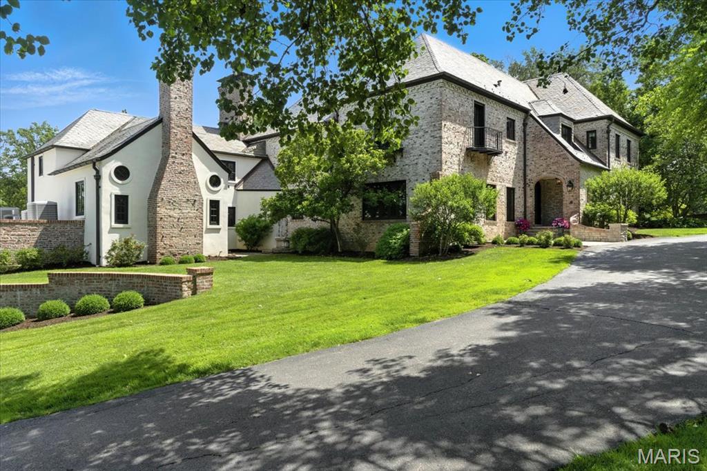 Welcome to the original home on the lane—a stunning French-style manor house that exudes warmth, charm, and timeless elegance. Nestled on 1.17 beautifully landscaped acres, this one-of-a-kind residence offers over 6,000 square feet of refined living space, rich with architectural detail and historic character.
Step inside to a gracious living room anchored by a stately stone fireplace, perfect for intimate gatherings or grand entertaining. The gorgeous step-down dining room is ideal for special occasions, while the updated kitchen and breakfast room perfectly balance functionality and style. The main level also features a cozy family room with a gas fireplace, a private office, and a warm, inviting den with its own fireplace and dry bar—an ideal space for relaxing or hosting guests.A serene three-season room overlooks the manicured grounds, creating a seamless indoor-outdoor living experience. Upstairs, the home features 5 spacious bedrooms and 4 full baths, including a beautifully updated primary suite with a luxurious bathroom and a top-of-the-line custom closet. Additionally there is a  2nd floor laundry.  The 3rd floor has a large rec room. Outside, enjoy complete privacy in the professionally landscaped gardens and expansive backyard. A circular driveway and three-car side-entry garage offer convenience and curb appeal. This warm and uniquely historic property is a rare opportunity to own a truly exceptional home in an unbeatable location.