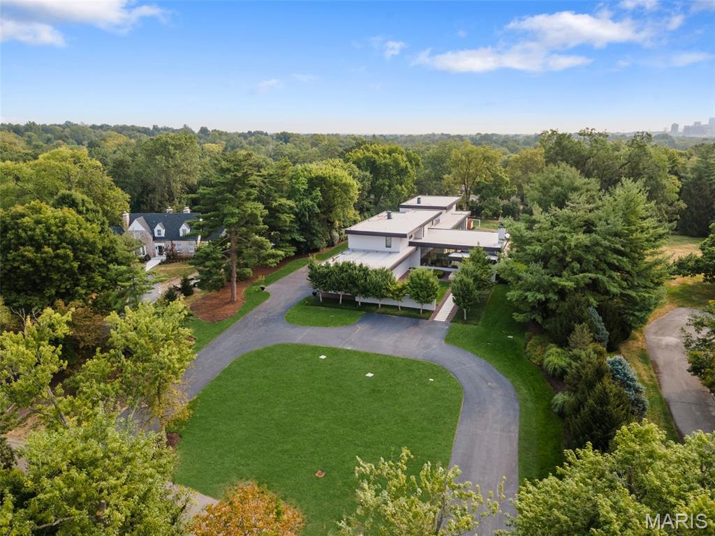 GREAT NEW PRICE.  NEW LOOK!  Secluded on a private lane in Ladue, this rare, 12-year-old modern architectural gem boasts over 10,000 sq ft with floor-to-ceiling windows flooding the home with natural light, accented by 14 ft ceilings and high end finishes throughout. The sophisticated great room is perfect for entertaining, while the art gallery with bar area provides additional options for your guests.  The brand new custom kitchen and walk in pantry offer high end appliances behind custom cabinetry.  Cleverly separated from the entertaining spaces, the private family living area offers a tranquil retreat featuring a main flr luxury suite with sitting room and his/her closets.   Find 4 bedrm suites and laundry on the 2nd level.  The lower level showcases a 2-lane bowling alley, media rm, large rec room with wetbar and a bedrm suite. Walk out to the saltwater pool and covered patio with fire feature.  An indoor basketball/pickleball court is perfect for a pickup game.  A 4-car garage, generator and more.   This home is a perfect setting for an art collection..
