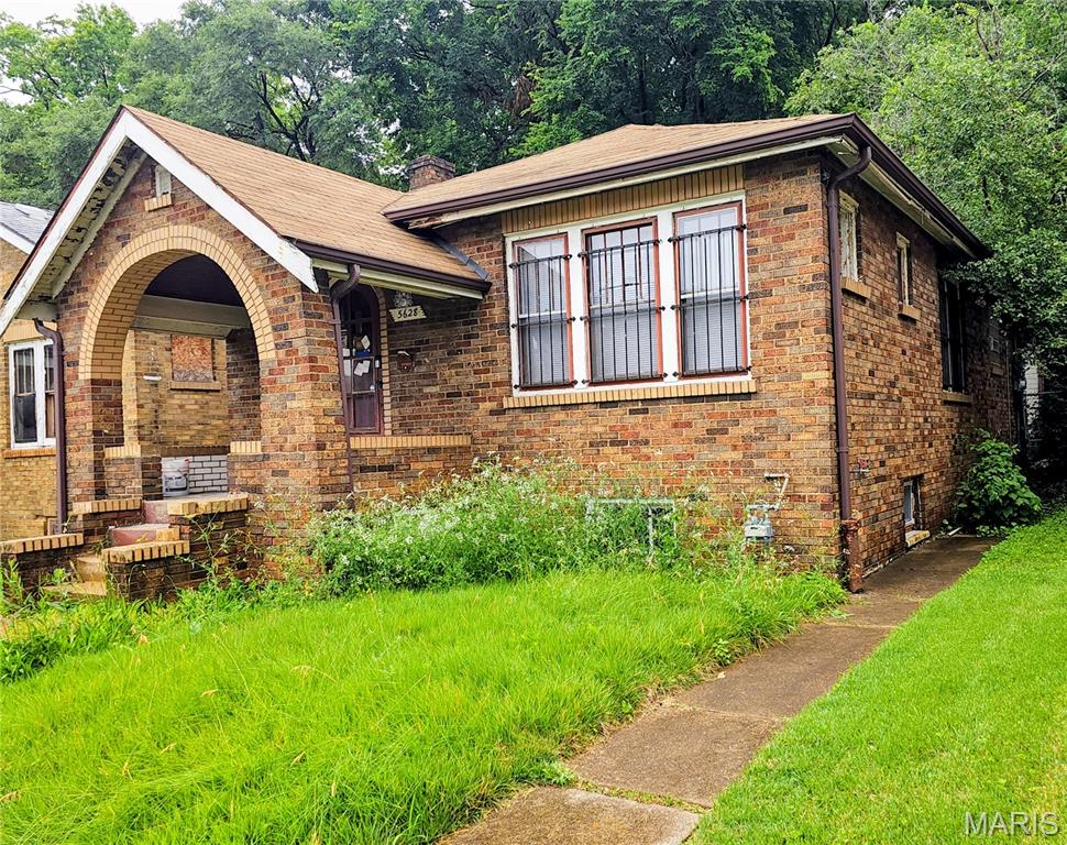 Here's a Quicker Fixer Upper! Step into the timeless charm of this classic Spanish-style brick bungalow, where architectural character and everyday convenience come together. From the inviting Brick Archway that welcomes you onto the front porch to the distinctive decorative glazed brick masonry, this home offers curb appeal that stands out from the ordinary. Inside, you'll find hardwood floors, 2 bedrooms, separate dining room and stunning stained-glass windows that fill the foyer and living room with warmth and character. The thoughtful floor plan combines vintage craftsmanship with practical living spaces, making this property ideal for homeowners seeking a unique residence, investors looking for a highly desirable rental opportunity, or to fix and flip. Additional features include a full walk-out basement offering abundant storage and future possibilities, as well as a detached oversized garage.  Location is another exceptional advantage. Situated in a highly walkable neighborhood, you'll enjoy easy access to everyday conveniences. Elementary school, Herzog Park, Lions Park, and Neighborhood Grocery
Stores are all just a short stroll away. Commuters will appreciate the home's proximity to public
transportation and quick access to Interstate I-70, providing convenient connections throughout the region. Properties with this level of architectural character, walkability, and accessibility are increasingly difficult to find. Whether you're searching for your next home or a smart investment opportunity, this charming bungalow deserves your attention. Schedule your private showing today—opportunities like this do not stay on the market for long! The home is being sold AS-IS; The seller will not provide any reports or perform any repairs. including municipal occupancy. A Hold Harmless will be completed before entering the home. Owner is a Realtor. No sight unseen offers.