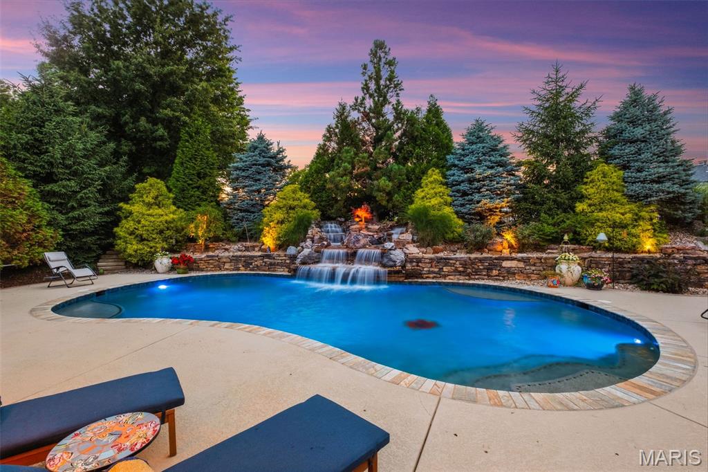 Back on market no fault of Seller, Buyer failed to perform.  Experience elevated living in this exceptional executive estate, where timeless brick-and-stone architecture meets resort-style luxury in an exclusive gated community Close to highways 364, 70 and Wapelhorst Park.

A grand foyer welcomes you into an expansive open floor plan designed for elegant entertaining and comfortable everyday living. The formal dining room impresses with its domed ceiling and statement chandelier, while the breathtaking great room features a dramatic wall of windows overlooking the sparkling pool with a rocked waterfall and professionally landscaped grounds. The home is equipped with a whole house airplay sound system.

The gourmet chef’s kitchen is a masterpiece, showcasing custom wood cabinetry, granite countertops, premium Viking appliances, a double gas range with pot filler, warming drawers, and an impressive double-island layout. Just beyond, the breakfast room is a wet bar and  flows seamlessly into the vaulted hearth room anchored by a stunning floor-to-ceiling stone fireplace.

Retreat to the luxurious primary suite featuring a coffered ceiling and a door to the pool. A spa-inspired bath with an oversized custom shower designed for total relaxation. A custom built walk in closet provides room to organize your items and includes 2 jewelry drawers, tons of hanging space and drawers.

The finished lower level offers the ultimate entertainment experience with a spacious recreation room, custom wet bar, fireplace, and built-in bookcases. Two large ensuite bedrooms, a private office, a large storage area and a dedicated workout room complete the space.

Step outside to your private backyard oasis, professionally landscaped for year-round enjoyment. Outdoor amenities include a covered patio, built-in grilling station, soaring fireplace, and a spectacular resort-style pool with a dramatic rock waterfall surrounded by lush gardens.

The 3 car garage provides space for all your toys with a 2 car garage that wraps to a 1 car garage both have room for additional storage. The garage has newer epoxy flooring.

This extraordinary home offers refined luxury, exceptional craftsmanship, and resort-inspired living at every turn.