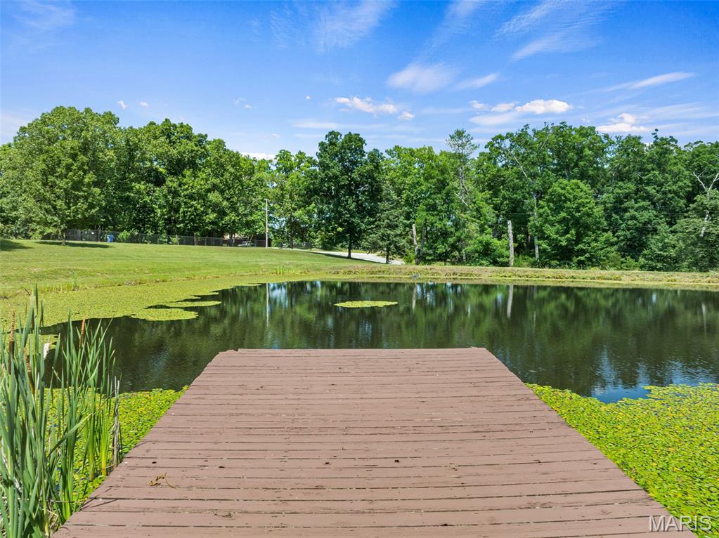 If paradise had a picture in the dictionary, this would be it!  Welcome home to your secluded piece of the country pie.  Spacious move in ready home nestled on 4.84 stunning acres, features private lake with dock and secluded lake views from neighboring property on the back side! Large expansive covered porch welcomes you in to your impressive vaulted great room. The star of the room is the floor to ceiling stone fireplace centered between dramatic sunburst windows  with lake views, or step out onto your deck and take in the stars and sounds of nature! Your updated kitchen features granite counters and beautiful mocha cabinets with stainless appliances that stay! With open concept giving you space for dedicated dining or expansive breakfast island seating!  Primary bedroom with lakefront views features new carpet, and large en-suite with separate shower or jetted soaking tub.  Two additional great size bedrooms also have new carpet and views of your front yard lake.  Main floor laundry just off garage for ease.  Full bath and an additional half bath complete this main level.  Retreat down to the fully finished LL complete with massive living room, two additional sleeping or flex rooms and a full bathroom make this extra space fully functional.  French door walk out to covered patio. Home features attached side entry 3-car, 840sf garage, plus detached outbuilding with electric and water and huge lean-to off back. Geothermal system updated 3 years ago. NEW ROOF getting installed!  Check back for interior photos.  HOME IS OCCUPIED, MUST HAVE APPOINTMENT WHEN SHOWINGS START 7/3. DO NOT WALK PROPERTY.