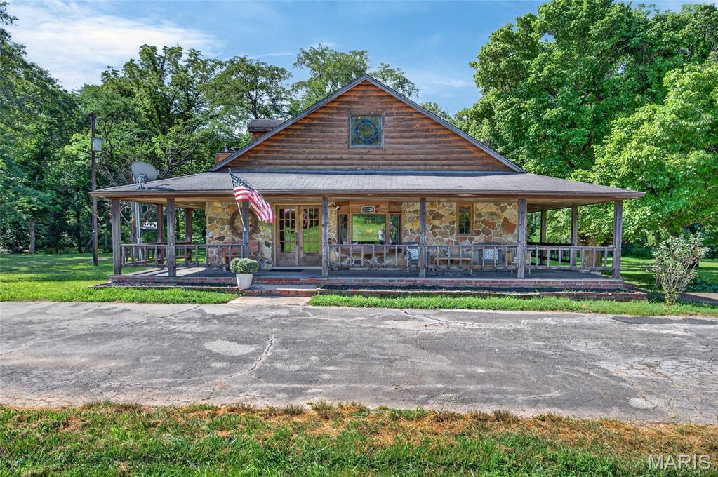 Own a piece of iconic Route 66 history with this one-of-a-kind estate nestled on 44+/- picturesque acres. Originally built around 1945, this remarkable property has been thoughtfully remodeled and expanded over the years. Once home to a general store and automotive garage, it has been transformed into a stunning residence that perfectly blends historic charm with modern comfort.

The main home welcomes you with a wraparound covered front porch, elegant French door entry, soaring 9-foot ceilings, beautiful wood floors, and an open-concept floor plan. Enjoy cozy evenings by the wood-burning fireplace or relax in the sunroom overlooking the scenic landscape. (Sellers have not used the fireplace, are not sure if it's working and selling it as-is)

The spacious upstairs primary suite features two walk-in closets, charming dormer windows, a private bath with an antique clawfoot tub, and an adjoining library complete with a vaulted ceiling, stained glass window, and abundant natural light.

Step outside to the partially covered back deck with pergula and take in peaceful views of the meadow with a gazebo, two spring-fed streams, and wooded surroundings.

The property also includes exceptional outbuildings. A finished two-car detached garage/workshop offers flexible space on both levels, with the main floor ideal for a workshop, studio, or spa, while the fully equipped loft apartment above—with a full bath on each level—provides excellent guest accommodations or rental income potential. A newly constructed detached three-bay garage adds parking for 2 more cars and a 3rd spot for utility vehicles or storage, and the concrete RV pad with full hookups makes hosting or traveling effortless.

The park-like acreage features two spring-fed streams, gazebo, storage shed, and a lean-to, creating the perfect setting for recreation, hunting, or simply enjoying nature. Best of all, the property borders the National Forest with direct access to a large access area, offering endless opportunities for outdoor adventure.

Rarely does a property with this much character, history, acreage, and versatility become available. Don't miss your chance to own this extraordinary Route 66 retreat.  Square footage and measurements are approximate REF DSC-8001. There is a wood furnace that was used for back-up heat, but it is no longer working and being sold as-is. See Seller's Disclosure - current main heat is electic with propane backup, plus mini-splits for additional heat. The workshop also has baseboard heat.