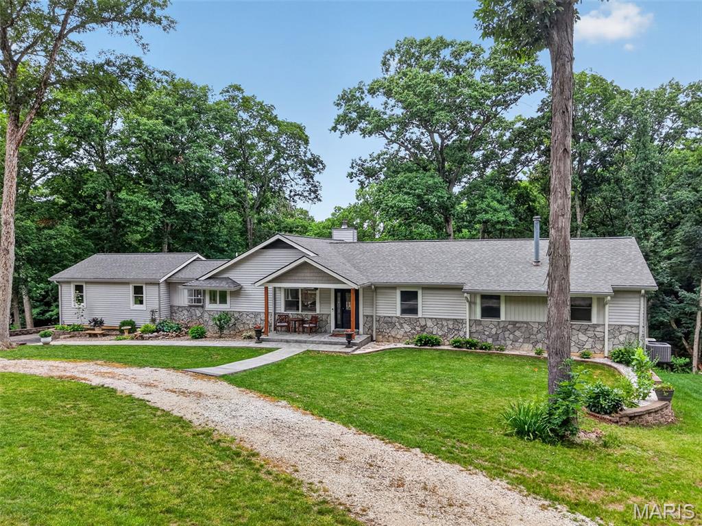 **SHOWINGS START 6/25**  Nestled on 3.22 picturesque wooded acres, this spacious ranch offers over 4,150 square feet of finished living space, incredible privacy, and the perfect blend of country living with neighborhood convenience. Located in a highly sought-after community where you'll regularly see neighbors walking, biking, riding golf carts, and enjoying the outdoors, this property delivers the lifestyle many buyers dream about.

Step inside to a vaulted great room featuring a floor-to-ceiling stone wood-burning fireplace and sliding glass doors and transom windows on both sides that frame the beautiful backyard views and fill the home with natural light. The kitchen offers an abundance of cabinetry, a center island, breakfast bar, corner sink overlooking the front yard, and an adjoining breakfast room. A separate dining room provides additional space for gatherings and entertaining.

The main level features four generously sized bedrooms and two full bathrooms. The secondary bath includes double sinks and a private shower/water closet, while the vaulted primary suite offers a private retreat complete with double vanities, jetted tub located in a bay picture window, separate shower, private water closet, and a spacious walk-in closet. A unique convenience is the direct connection from the primary closet to the main-floor laundry room, which includes additional storage cabinetry and a utility sink. The primary closet also features ladder access to extensive attic storage space.

The walkout lower level was completely renovated in 2021 and adds tremendous living space with a large recreation area, wet bar, two sleeping areas, and two full bathrooms—ideal for guests, multigenerational living, hobbies, or entertaining.

Car enthusiasts, hobbyists, and those needing extra storage will appreciate the two separate two-car garages, including a side-entry garage and a tuck-under garage. The tuck-under garage connects to the utility room and an additional storage room, providing exceptional functionality.

Recent exterior improvements include a brand-new roof, siding, and gutters. The home is move-in ready while offering an outstanding opportunity for cosmetic updates to add significant value and make it their own.

Enjoy the beauty of nature with a short walk through the woods leading to Indian Camp Creek. Chickens are permitted, making this property even more appealing. 

Properties offering acreage, privacy, over 4,150 square feet of living space, four bedrooms, two additional sleeping rooms, four full baths, four garage spaces, and this much potential are rarely available, especially at this price point. Don't miss the opportunity to create your dream home in an exceptional setting with fantastic neighbors.