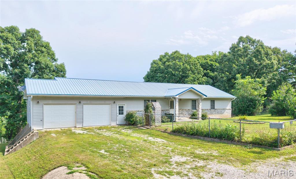 6.81 ACRES | POND | BARN | WALKOUT BASEMENT | PUBLIC WATER & SEWER | MINUTES TO FORT LEONARD WOOD! Escape to your own private retreat with this 3-bedroom, 3-bath ranch home offering 2,912 sq. ft. on 6.81 wooded acres in the Waynesville School District. The main level features a functional floor plan, while the walkout basement includes a dedicated John Deere room with French doors, ideal for lawn equipment, ATVs, a workshop, or extra storage. Outside you'll find a large private stocked pond with catfish and bass ( approximately .5 acre), covered front porch, fenced front yard, partial rear fencing, oversized 29' x 28' attached garage, 42' x 40' shop building with concrete floor, lights and ample 110 and 220 outlets for available power supply, insulated, with a large exhaust fan, this shop building is a dream for a mechanic, machine shop, fabricator, service business owner, cabinet  maker, etc..  26' x 13' two-story outbuilding with a concrete floor on the lower level, 20' x 26' covered carport, 18' x 21' enclosed carport with concrete floor and power, and 10' x 17' storage shed with a concrete floor. Whether you're looking for a hobby farm, recreational property, homestead, or simply room to spread out, this property offers the acreage, privacy, and outbuildings today's buyers are searching for. All just minutes from Fort Leonard Wood, shopping, dining, and everyday conveniences.