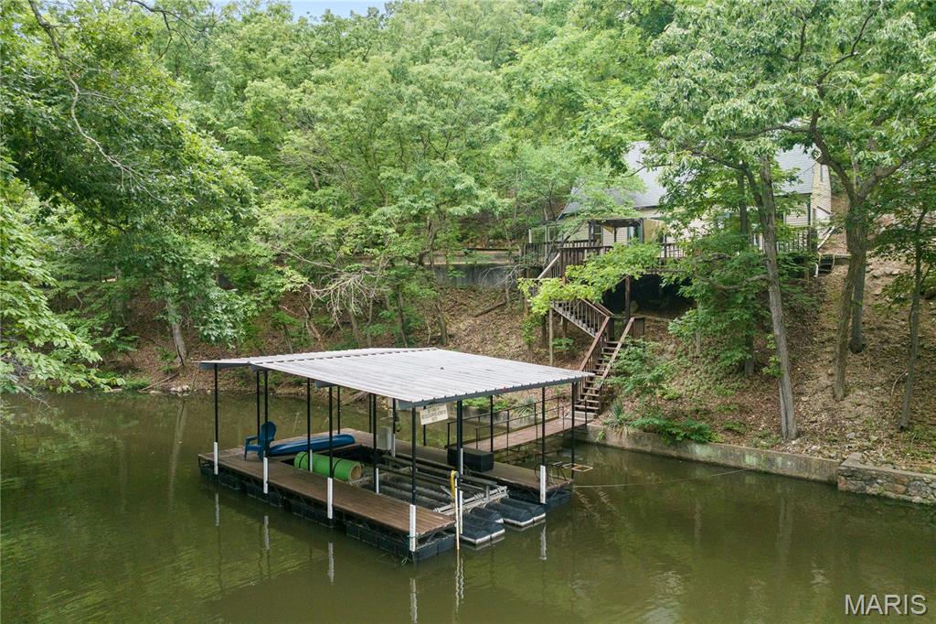 Have you always dreamed of owning a lakefront home? Seize this incredible opportunity at an unbeatable price! Nestled in Sunrise Acres 1 at the 9MM, this tranquil and private open-concept residence features 2 bedrooms and 1.5 bathrooms, perfectly designed to maximize your lakefront experience. Enjoy 100 feet of cove-protected lakefront situated near a convenient boat ramp.
The outdoor space is an entertainer's dream, boasting an expansive deck area and a single-well (10x24) dock complete with a 10,000-pound hoist. Additional property highlights include ample flat parking, low-maintenance city water and sewer hookups, and quick access to a variety of nearby amenities. While nightly rentals are not permitted, long-term rentals (14+ days) are allowed, offering excellent flexibility and investment potential for savvy buyers. Whether you are looking for a peaceful full-time residence, a private weekend getaway, or a steady long-term income producer, this turn-key property delivers the perfect lakefront lifestyle. Don't miss your chance to own a piece of the lake at an affordable price point—schedule your private tour today!