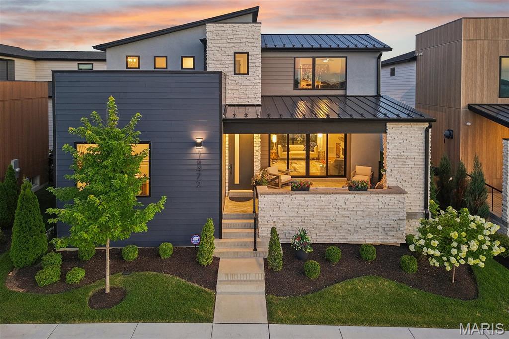 Built in 2023 by McKelvey Homes, this custom contemporary home sits on the water in Waterfront at Wildhorse Village, one of only 35 custom contemporary/modern homes in the enclave. A design concept without comparison elsewhere in the St. Louis region. This northwest facing, 4-bedroom, 2.5-bath home offers 2,684 sq ft with Pella windows offering serene lake views from the living room, kitchen, office and one upstairs bedroom. Large sliding glass doors open the living room to a front covered lanai for indoor/outdoor living directly over the water, while a covered back porch overlooks a private courtyard complete with a fireplace, arbors, a footbridge, and mature plantings and hardscape.
The kitchen is built around an expanded waterfall-edge island with a Wolf gas cooktop with a noise-reduced downdraft vent, floor-to-ceiling two-tone cabinetry with crown molding, GE Cafe French door wall mount ovens double wall ovens, Samsung Bespoken refrigerator with beverage center, and quartz countertops. The adjoining dining area opens to the courtyard and includes a serving area with a wine fridge and matching quartz counters. A walk-in pantry with convertible Galanz retro fridge/ freezer and walk-in laundry room with GE washer and dryer with under storage sit just off the kitchen, with a main-level office/front bedroom and half bath completing the floor plan. A covered breezeway links the back-loaded 3-car garage to a landing space, the primary bedroom, and the kitchen for direct main-level access.
The main-level primary suite includes a soaking tub, large shower, private toilet room, double vanities, and a walk-in closet with a custom closet system, with the bedroom itself facing the courtyard. A convenient access from the primary ensuite to the garage was added to the floor plan for functionality. 
Upstairs, two additional bedrooms, a full bath, and a study nook complete the home; the lower level is unfinished, with an egress window and bath rough-in already in place.
The community sits adjacent to two small lakes, with parks and recreational trails nearby, Chesterfield Amphitheater approximately 0.5 mi away, and a YMCA approximately 0.2 mi away. I-64 access is approximately 1 mi out, and The District and Chesterfield Commons shopping complex is approximately 2 mi away. The ongoing Chesterfield Mall redevelopment — a planned $2 billion, 4.5-million-square-foot mixed-use project with a central park, residential units, retail, dining, and entertainment — is positioned to become Chesterfield's new downtown. Includes 3D walkthrough and floor plan.