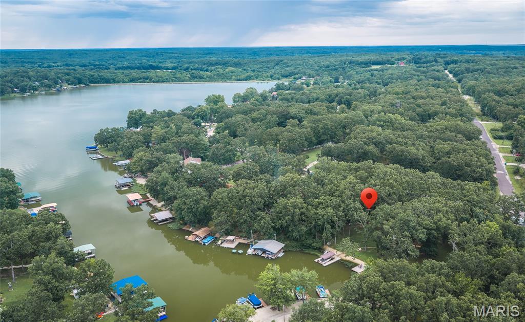 Welcome to Lake Life! This Quaint four bedroom, two bath home on a PRIVATE TRIPLE LOT is being sold TURN KEY!! You, your family and guests will love the level backyard perfect for outdoor activities with large storage shed. Covered Dock stationary dock, seperate Swim Platform/Sun Deck makes it easy for access to the water and don't miss the stone Firepit for relaxing evening gatherings by the fire. Coming in the front door, you walk into the spacious living room with wood burning fireplace. Sliding doors from this room take you to the large deck with a view of the lake and enormous flat backyard. Up a small flight of stairs, you will find a spacious 2nd living room, the primary bedroom/bath, 3 more bedrooms and another full bath. Lower level has kitchen/dining rooms, walk out to yard and spacious laundry/storage room. The lake offers 326+/- acres of fun for boating, fishing, skiing, tubing, swimming, kayaking for just floating! Community has a full service marina, beach/playground, community center, tennis and pickleball lighted courts, basketball, volleyball. Community hosts year round gatherings of potluck, music, trivia nights, etc. for members to use. This is one you won't want to miss!!!!