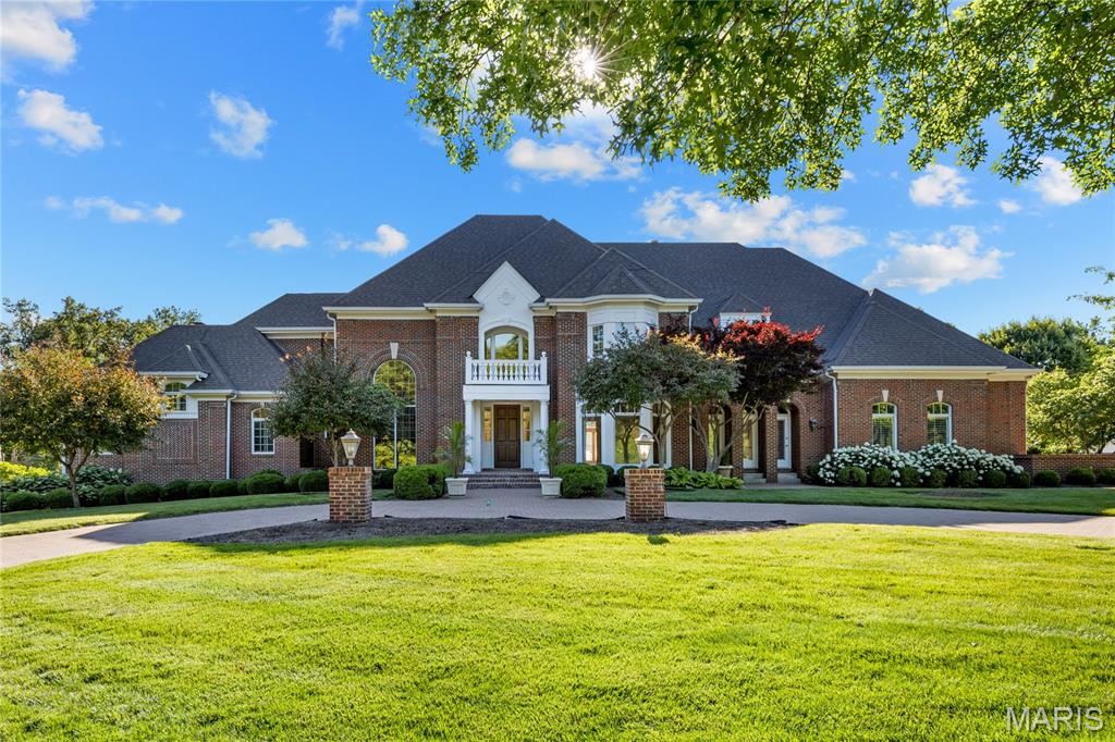 Situated on a parklike 1+ acre lot in gated Manderleigh Estates, this magnificent Georgian-style residence from Johnson Homes gracefully blends classic architecture with contemporary design elements. Custom trim work accents grace each room & complement the superior craftsmanship evident throughout the home. Impressive herringbone brick porch entrance with architectural columns & balcony leads to grand 2-sty foyer, well-appointed study surrounded by natural wood paneling & bookcases and elegant dining room with wide bay window. Architectural pillars, soaring windows & a cast stone fireplace set the tone for the stunning great room. Designer kitchen with marble countertops, custom bisque cabinetry, professional grade appliances & 9’ center island adjoins light-filled breakfast room with convenient planning center. The coffered primary bedroom suite radiates warmth with a slate fireplace, 2 customized walk-in closets, marble bath with jetted tub & private deck. Front & rear staircases access a 2nd primary suite with spa-inspired bath and 2 additional ensuite bedrooms. Lower Level entertainment space includes recreation room with floor-to-ceiling brick fireplace & 12’ wet bar, theater room & billiards room plus office, 5th & 6th bedrooms with Jack n’ Jill bath & full bath with steam shower. French doors open to inviting outdoor living area with expansive deck, covered patio & resort style pool surrounded by landscaped gardens.