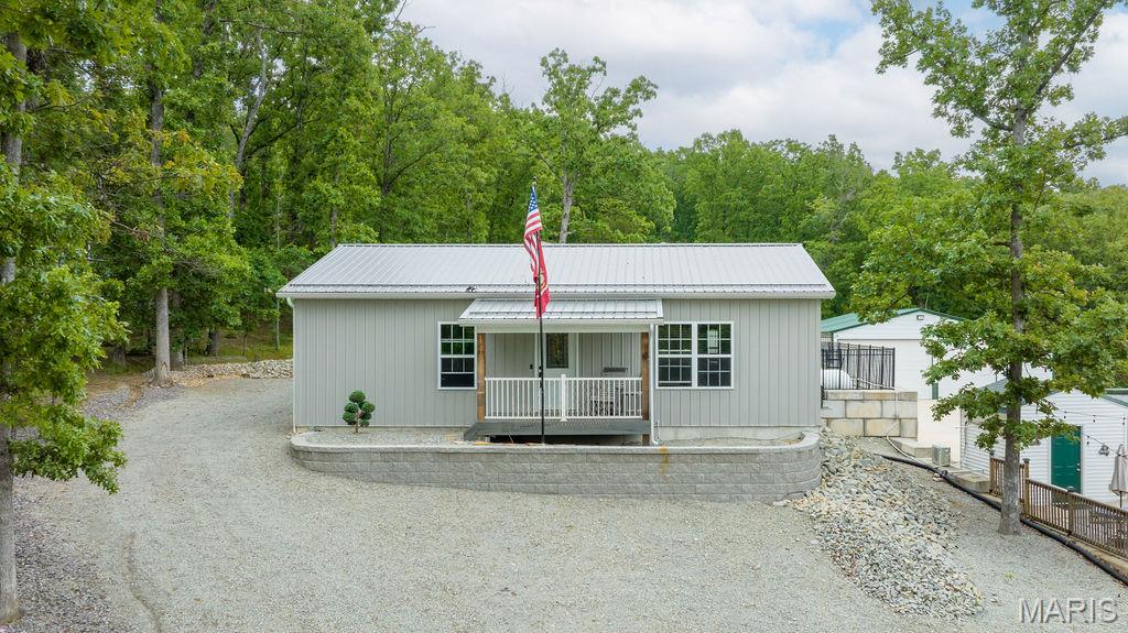 This wonderful lake community home brings a sense of coziness to the outdoors. Recently built in 2023 offering 2 bedrooms and 2 full baths and is sitting on 2 beautiful lots. The long driveway sets the tone with tons of landscaping details surrounding this property. A nice covered front porch leads you into an open floor plan with a spacious living room with a knotty pine ceiling, custom lighting and natural lighting from the double window. The eat-in kitchen is complete with a dining area, custom Amish-Made white cabinets, granite countertops, stainless steel appliances and a breakfast bar. Master bedroom is large with a private full bathroom that has been gorgeously done with a tiled step-in oversize shower. large vanity with tons of storage space and a walk-in closet. There is a second nicely sized bedroom and additional full bathroom. The laundry and mud room is at the back of the home leading out to a private deck that is attached to the detached 30x40 steel building. This workshop/garage is nicely set up for all your storage needs with 2 garage doors, heating & cooling system, tons of space for any hobby and beautifully surrounded with cleared ground for outdoor storage needs for a RV and boat. Enjoy all the amenities for this lake community including year-round events, access to the 400+ acres lake and smaller lakes, playgrounds and surrounding nature. Do not hesitate to see what this lake property has to offer, make your appointment today!
