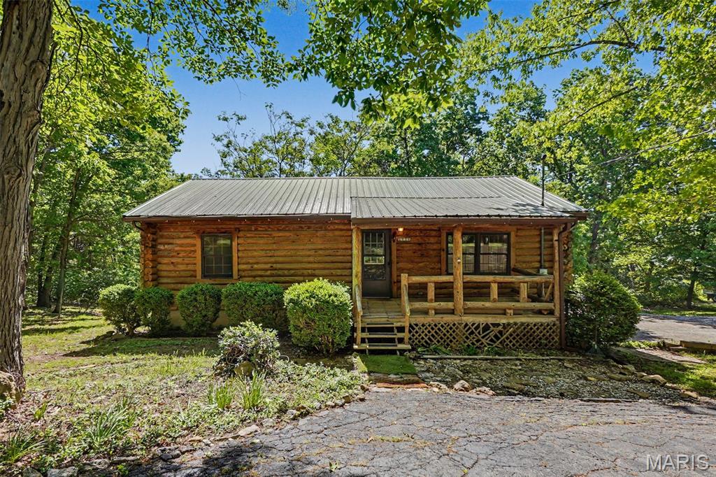 Tucked away on 6+ beautiful acres in House Springs, this charming log home offers the perfect mix of privacy, character, and peaceful country living. Surrounded by trees with a creek running through the wooded portion of the property, you'll love the scenic setting and space to explore, hunt, or enjoy the nature this property has to offer. Step inside to find cathedral ceilings with stunning wood beams and a gas fireplace. This 2 bedroom, 1.5 bathroom home also includes a covered front porch, covered back deck, fenced backyard, a 2-car garage, and another detached 2-car garage with workshop! A little TLC would make this home really shine. Property is being sold as-is.