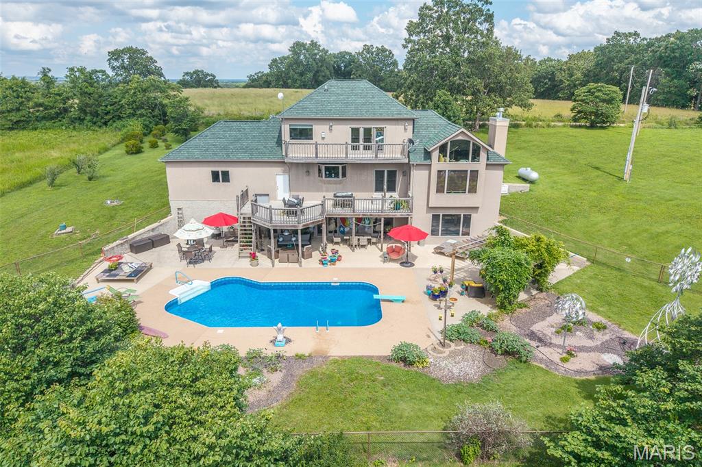 Welcome to your private country retreat on 20.28 picturesque acres in Richland, Missouri. Surrounded by rolling pasture, mature trees, and abundant wildlife, this custom-built 4,000+ sq. ft. home offers a rare combination of luxury, craftsmanship, efficiency, and functionality.

A grand custom entry featuring an elegant oval beveled-glass door with matching sidelights and an arched transom sets the tone for the quality found throughout. Inside you'll find soaring ceilings, Anderson windows, solid 6-panel blond oak doors, bamboo flooring, and a unique observation loft overlooking the main living area with sweeping views of the surrounding countryside. Multiple rooms feature programmable full-spectrum LED recessed lighting controlled from your phone or tablet.

Built with quality and efficiency in mind, the home features 2x6 construction, spray foam insulation, a backup generator, 400-amp electrical service, owned solar panels, and a whole-home Sonos sound system. The spacious floorplan includes 3 bedrooms, 2.5 baths, propane fireplaces, a storm shelter room, stairlift system, and a walk-out lower level with attractive epoxy-sealed decorative concrete flooring. No wall-to-wall carpeting.

The custom kitchen showcases solid maple cabinetry finished in striking Prussian Blue, soft-close drawers, hidden pull-out spice storage, oversized pot drawers, and a floor-to-ceiling pantry with accessibility shelving. A Vermont Quarries soapstone farmhouse sink is complemented by a hammered copper prep sink and beautiful maple butcher-block countertop. Cabinetry was originally designed to accommodate a future dishwasher installation.

Outdoor living is equally impressive with a heated saltwater inground pool, expansive patio, pergola, beautifully landscaped flower gardens, and peaceful country views in every direction. Whether entertaining guests or enjoying a quiet evening at home, the outdoor spaces were designed to be enjoyed year-round.

With six enclosed parking bays between the attached three-car garage and the separate three-bay shop complete with electric and HVAC, this property is ideal for hobbyists, car enthusiasts, entrepreneurs, or anyone needing additional workspace and storage. The acreage offers a blend of usable pasture and wooded areas, creating opportunities for recreation, livestock, gardening, or simply enjoying the privacy and beauty of country living.

A true four-season birdwatcher's paradise, abundant wildlife can be enjoyed from the home, observation loft, and surrounding grounds throughout the year.

This exceptional property delivers quality construction, energy-conscious features, resort-style outdoor living, and a lifestyle rarely found in one offering.