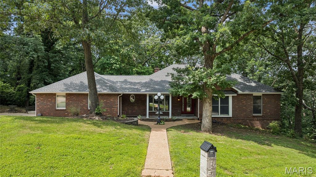 Custom-built ranch on 1.17 wooded acres in unincorporated Jefferson County, offering exceptional privacy on a quiet private country circle with only three homes. Ideally located between Fenton and Arnold, this peaceful retreat combines a secluded setting with easy access to shopping, dining, and everyday conveniences.
The inviting covered front porch welcomes you into an open floor plan featuring formal living and dining rooms, a vaulted great room with a stunning two-sided see-through fireplace, and French doors leading to a maintenance-free Fiberon deck overlooking the wooded lot. The oversized updated kitchen includes abundant cabinetry, a bay-window breakfast area, and a second set of French doors to the deck. Main-floor laundry with washer and dryer leads to the oversized three-car side-entry garage.
The main level offers three spacious bedrooms, including a luxurious primary suite with a fireplace, bay-window sitting area with soaker tub, separate shower, double vanity, and walk-in closet. The finished walkout lower level features a large family/rec room with numerous windows, access to a private deck, a fourth bedroom, full bath, and flexible space perfect for guests, a home office, or recreation.  As a bonus, there is also a large walk-in cedar closet.
Recent updates include a newer roof, front entry door, kitchen, and beautiful wood flooring. Enjoy custom craftsmanship, scenic wooded views, and a prime location with quick access to Hwy. 141, shopping, dining, and everyday conveniences.
Swim Spa not included.