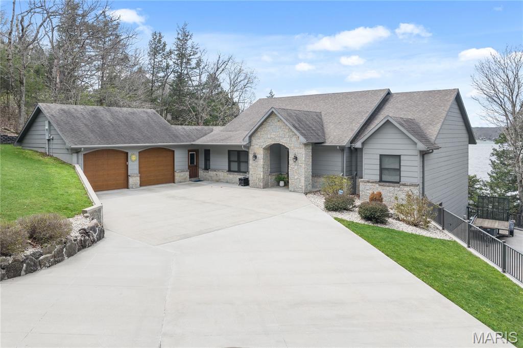 Experience luxury lake living at its finest in this remarkable Signature Homes ranch walk-out, perfectly positioned at MM 4 of the Gravois Arm. Boasting 211 feet of pristine shoreline & unrivaled sunset views, this 4-bed, 3-bath retreat delivers ultimate privacy & sophisticated style in Rocky Mount. The heart of the home is a French Country chef's kitchen flowing into an open living space w/engineered hardwood & a whole-house speaker system. The luxurious primary suite features his-n-her closets & a spa-like ensuite. The lower level is an entertainer's dream, featuring a wet bar, a wine cellar with a custom handmade wood door, and a unique fireplace crafted from the stones of the property's original cabin. Step outside to a gentle, level walk to the large dock (featuring 11x30 and 10x20 slips, two hoists, and a swim platform) with layered rock shelving at the water's edge. Relax in the enclosed sunroom or by the massive fire pit area. The expansive concrete driveway parks 12+ vehicles and includes a 220V RV outlet. Located near favorites like Lake Burger, Jolly Rogers, Coconuts, and Maggies, every detail of this lakefront gem exudes quality. Your private, secluded sanctuary awaits!
