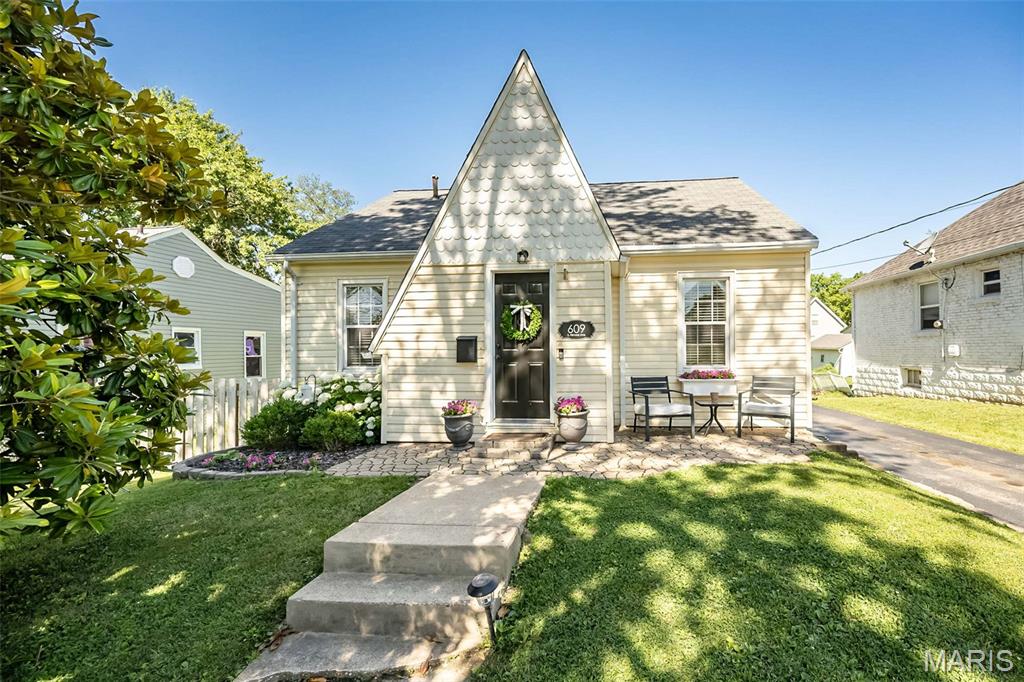 609 S. Fillmore Ave. ~ Storybook charm meets modern-day style in this DARLING gem located in the heart of Kirkwood! Bursting with character and personality, this beautifully updated home showcases designer finishes, thoughtful upgrades and a curb appeal that will steal your heart! A warm welcome begins at the inviting stone-paved entry and quaint sitting area where a distinctive peaked facade, accented with unique scalloped detailing is beautifully framed by the magnificent magnolia tree and vibrant blooming hydrangeas. Step inside to the thoughtfully designed entry foyer featuring custom built-ins and a convenient coat closet providing excellent extra storage for everyday essentials. An arched doorway leads you into the gorgeous living room that's a cheery sun-lit space with rich hardwood floors and warm neutral color palette that creates a comfortable atmosphere. The elegant dining room ~ originally a third bedroom ~ showcases a chic chandelier and a large closet that provides additional storage. The primary bedroom offers ample closet space and easy access to the nicely appointed bathroom featuring a designer cabinet vanity with luxe gold accents/hardware, large tub/shower combination with attractive tile surround and built-in niche for added convenience and style. Love to cook? The well-equipped kitchen is FABULOUS featuring custom buttercream Diamond cabinetry, striking abstract tile backsplash, sleek solid-surface countertops and nicely sized pantry. Upstairs you’ll find a spacious second bedroom with ample closet and storage space offering a comfortable retreat to relax and unwind. The lower level provides wonderful flex space, ideal for a home office, guest sleeping area or rec/family room offering versatility to suit your needs. Head out back to the GORGEOUS fenced yard with mature trees and plenty of space to play ball, entertain or simply relax. The one-car detached garage is an added bonus providing extra parking and convenient storage. Let’s not forget the PRIMO location ~ just one block to Fillmore Park and only 5–6 blocks to vibrant Downtown Kirkwood that offers an abundance of restaurants, boutique shopping, Farmer’s Market, YMCA, library, and so much more!