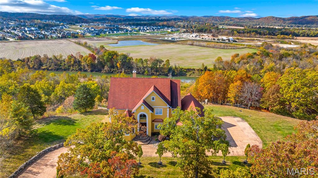 Immerse yourself in the vibrant colors of autumn from your new home perched above the Meramec River Valley, where brilliant panoramic views of the Ozark Highlands’ foothills unfold in every direction! This architectural masterpiece offers 6 bedrooms and 6.5 baths, with most rooms framing breathtaking views. Double mahogany doors welcome you into a grand two-story foyer with a sweeping staircase and durable hickory floors. A unique pneumatic elevator provides effortless access to every level. The heart of the home, a majestic two-story great room, features a fireplace with onyx accents, built-in bookcases, and French doors opening to a balcony above the infinity saltwater pool that blends into the horizon. Gourmet experiences await in the kitchen with premium appliances, granite counters, and a glass block center island with fiber optic lighting. The main-level primary suite is a haven for relaxation with a jet tub, shower, dual vanities, and private balcony access. Glass French doors open to an upper-level bedroom that doubles as an office & conference area. Descend into a world of fun and comfort on the lower level. Perfect for family and guest entertainment w/ a full 2nd kitchen, games area, wine, & exercise rms. After a day relaxing by the infinity pool, freshen up in his & her locker rooms then settle into one of 12, tiered empress chairs for an unforgettable movie night the home theater.
