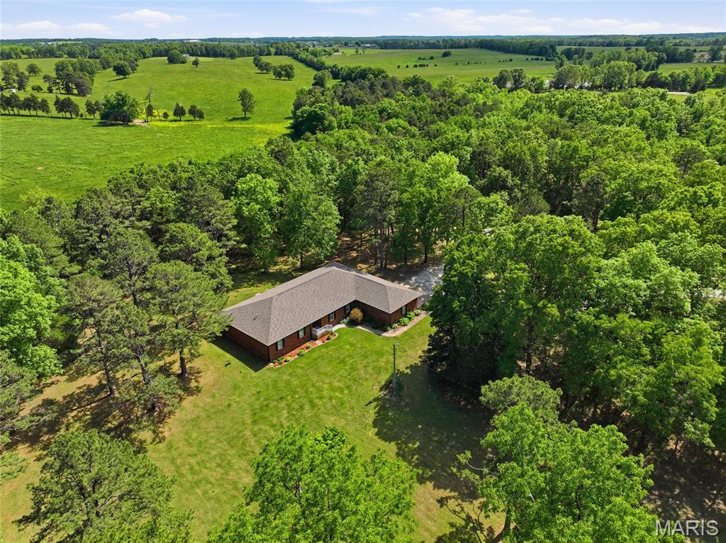Tucked away on 6 beautifully maintained acres that feel more like a private park, this stunning 3-bedroom, 3-bath home offers the perfect blend of peaceful country living and everyday comfort. Mature trees, gently rolling landscape, and wide-open green space create a setting that invites you to slow down, relax, and enjoy the beauty of nature right outside your door. Inside, the heart of the home is the spacious eat-in kitchen designed with both function and gathering in mind. Featuring a center island, walk-in lighted pantry, and French doors leading to the covered back porch, this space flows effortlessly for entertaining family and friends indoors and out. Whether it’s morning coffee overlooking the property or summer cookouts on the patio, this home was made for making memories. The oversized living room offers incredible flexibility with room for a large dining table, multiple seating areas, and comfortable everyday living. The main bedroom suite is truly a retreat of its own, highlighted by a stunning wall of windows and doors that open directly to the covered back patio, bringing natural light and scenic views into your private sanctuary. Beyond the beauty, this property also offers major recent upgrades for peace of mind, including a new heat pump HVAC system installed just one year ago, two hot water heaters replaced within the last year, and a brand-new septic system and holding pond. The impressive 32x48 shop building with attached 12x48 lean-to is fully equipped with concrete floors, electric, storage cabinets, and even a heated 3/4 bath — perfect for hobbies, equipment, or recreational toys. Properties like this don’t come around often — schedule your private showing today and experience the lifestyle this incredible acreage property has to offer!