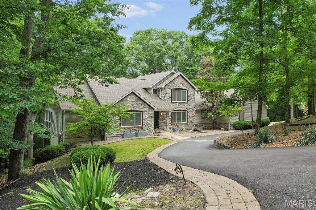 A rare opportunity to own a private wooded retreat with room to live, entertain, expand, and truly escape—without sacrificing convenience. Nestled on over 3 serene acres along a private road in the highly sought-after Rockwood School District, this exceptional custom home offers over-the-top versatility with 5 bedrooms, dual staircases, an attached 3-car garage, multiple gathering spaces, and a finished walkout lower level designed to evolve with your lifestyle.

Inside, dramatic architecture steals the show with soaring cathedral wood-beamed ceilings, a striking stone fireplace, and walls of windows framing peaceful wooded views. The spacious kitchen showcases custom cabinetry, quartz counters, tile flooring, updated sink, and updated dishwasher, while the adjoining 4-season room creates the perfect cozy retreat year-round.


Versatile Luxury Living !
The main floor features TWO primary suite options, including a luxurious owner’s suite with heated tile floors, soaking tub, separate shower, and walk-in closet. Upstairs offers spacious secondary bedrooms, full bath, and study nook overlooking the Great Room.

Outdoor living shines with expansive decks, stone pathways, patio, and firepit spaces designed for unforgettable evenings under the trees. Fresh paint throughout, updated water heater, updated water softener, and a beautifully updated driveway make this home move-in ready. No HOA restrictions mean the acreage is yours to dream, create, and enjoy however you choose.
