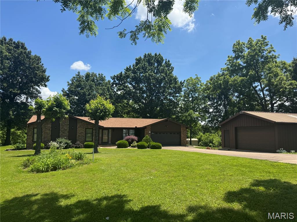 Country living on 5.21+/- level STUNNING acres in unincorporated Defiance! A tree lined driveway leads to a CHARMING, RANCH home with 3 bedrooms, 2.5 baths & 1,978+/- SqFt of living space that offers an AWESOME, 30’ x 24’, 2-car, detached garage & shed. Partially covered front porch greets you as you step inside the entry foyer. Step down, living room boasts a floor-to-ceiling brick wood burning fireplace, 14’+/- vaulted ceiling w/wood beams & dry bar w/custom cabinetry. Breakfast room features wood railing overlooking the living room & sliding glass walk-out to patio allowing plenty of natural light. Eat-in kitchen offers custom cabinetry, white appliances, Formica “wood like” countertops & laminate “tile like” flooring. Primary suite with carpet & ensuite full bath with shower w/sliding glass doors, 2 single sink vanities (1 w/make alcove), walk-in closet & linen closet. Other 2 bedrooms with carpet, slide closets & share hall bath with shower/tub & single sink vanity. Dining room & laundry/half bathroom completes the main level. Unfinished lower-level has great potential for additional living space awaiting your finishing touches with 8’+/- ceiling. Within the Francis Howell School District & easy access to HWY DD & HWY F. MUST SEE!