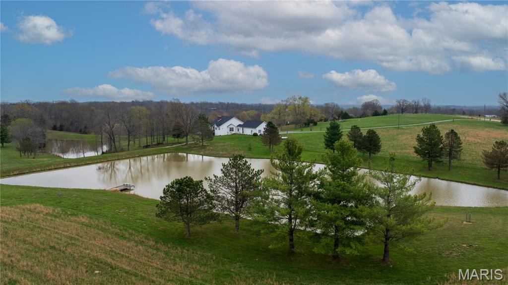 Welcome to your personal slice of paradise!  A peaceful retreat... spacious hobby farm... permanent getaway.... This is the relaxing setting that dreams are made of!  60 private acres with 2 scenic lakes provide beautiful views all year round, sunrises on the front porch and stunning sunsets out back reflecting on the water!  Wildlife sightings, TONS of cleared usable acreage, secret forest trails, 30x50 detached building on a concrete slab with two 14 foot tall sliding doors, RV hook-up and storage, a professionally-built raised bed garden with a deer-proof fenced perimeter, whole house generator, energy efficient geothermal system, 2 wells... and SO much more!  The custom designed home was carefully planned with quality construction and craftsmanship by local builder Tim Estes, less than 20 years ago!  5 bedrooms, 3 full bathrooms, 3-car attached oversized garage (29x35), 3 fireplaces, 4,655 square feet of living space, and such a great layout for hosting and entertaining!  Tall cathedral ceilings in the Great room make for a large statement fireplace with floor-to-ceiling decorative stone!  Very nice and open floor plan combines dining, kitchen, family room and doors leading out to a concrete deck on brick columns with a patio underneath! And a SunSetter remote controlled awning for shade on those sunny summer days on the deck.  The custom kitchen is beautiful and functional offering an abundance of storage, cabinets and Silestone countertops, an L-shaped island with a second sink, breakfast bar and stool seating.  But BEST of all is the view... 3 sides of windows in the kitchen bay provide the best panoramic views of the lakes, the land and the sunsets!  Other main floor features are:  the laundry/utility room, a mudroom breezeway off the garage, and a large master ensuite with lake waterfront views!  The ensuite has coffered ceilings, a cozy gas fireplace, direct access to the deck and a huge walk-in closet!  The primary bathroom has double sinks with a middle vanity, water closet, separate shower and jet tub.  Heading to the lower level, you'll find a spacious family room with a wood-burning stove fireplace!  And 4 bedrooms with a full bathroom provides an inviting space for guests to stay a while and have a private space to lodge.  Multiple walk-outs lead from the lower level family room to a large patio covered by the deck.  Right off the patio is a built-in fire pit and 60 acres waiting for an adventure, a fun family day exploring, recreational activities, target shooting, fishing, 4-wheeling, whatever you daydream about can be your personal oasis here!