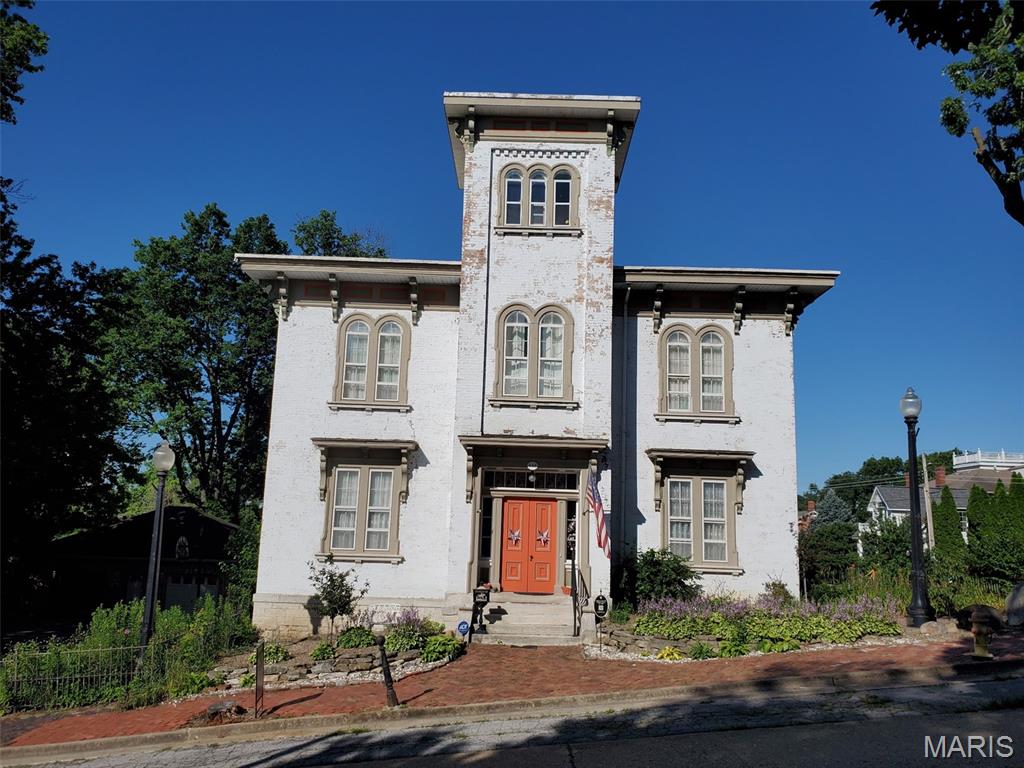 If these walls could talk, they would tell elaborate stories that encompass almost 170 years from tall tales to historical facts.  This Grand Historic Italianate style solid brick beauty was built in 1858 by James H. Johnson, a riverboat captain.  Other owners include John B Henderson (author of the 13th amendment) and Paul C Stark Sr of Stark Bros Nurseries.  This home has been lovingly preserved with the majority of original details plus modern amenities added.  Enter into the foyer through solid wood double doors and be transported back in time. Slowly make your way into the grand center hall with a view of the floating stair, glistening chandelier (relocated from the Visitation Academy of St. Louis by Theodosia Stark in 1945) and be astounded by the massive floor to ceiling mirror (relocated from the Peak Mansion in St. Louis by Captain Johnson) The majestic ballroom once used to entertain historical dignitaries boast ornate details, 2 fireplaces, walkout windows to the deck, and original interior shutters. The entire home is graced with 14-foot ceilings, and the 3rd story offers a cupola (find the hidden signatures of past owners) with a view of the mighty Mississippi River.  Enormous foldable pocket doors grace most rooms; 9 fireplaces with gorgeous mantels, and original plaster medallions ornately enhance the chandeliers throughout. Original summer kitchen was converted to a main floor suite.  Main floor kitchen was recently updated with all modern necessities. The back stairs lead to a second kitchen that once housed the indoor servants.  4 massive bedrooms with adjoining pocket doors located on the second floor each having its own fireplace.  Grand floor to ceiling library in the second-floor hall. The 2-story covered decks on the back of the home can be accessed through many doors and provide ample entertaining space.  Oversized 2-car brick detached garage with workshop area. Seasonally landscaped lot is enhanced with wrought iron fencing and original hitching post.  This stately residence has been featured on many historical tours and can easily be utilized as a B & B, wedding venue, multi-generational living, or your personal historical residence.