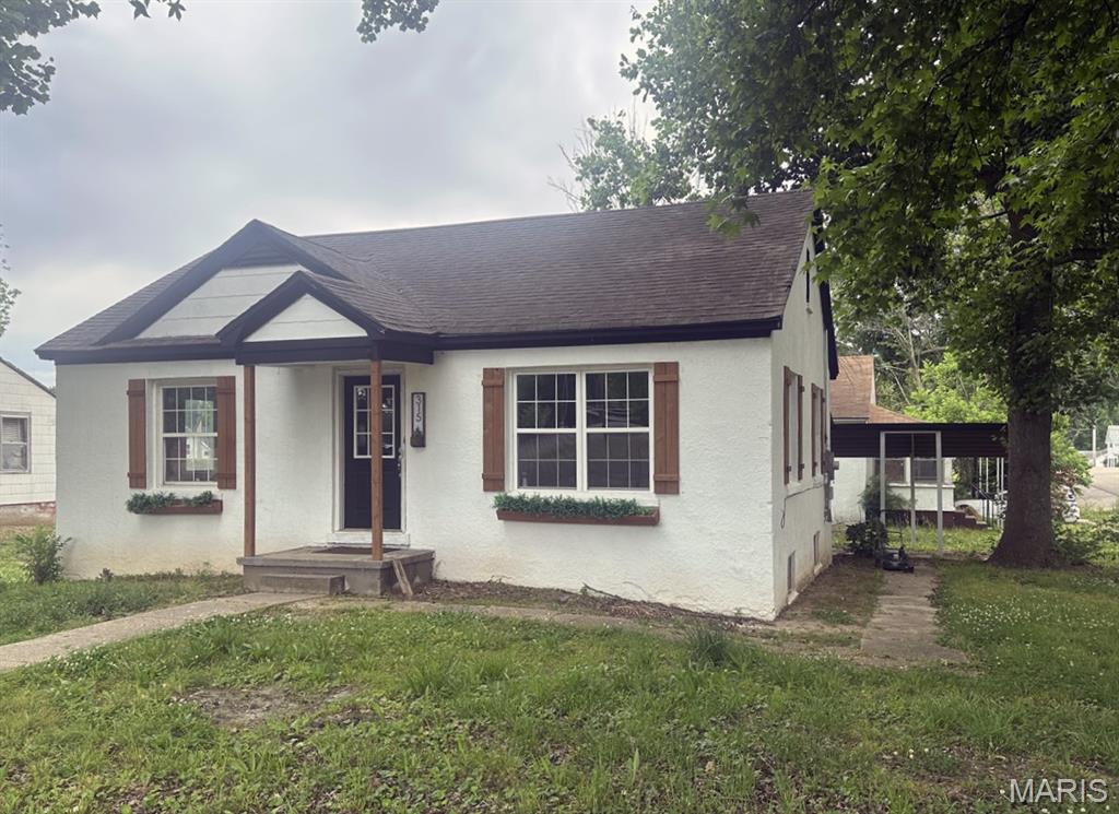 This charming bungalow on a corner lot is full of curb appeal and inviting character. Featuring an architectural shingle roof, stucco exterior, and a screened/glassed 9.8 x 8 porch, this home offers comfort inside and out. The thoughtfully selected interior paint colors create a seamless flow from room to room, complemented by beautiful laminate wood-look flooring throughout. Ceiling fans add comfort in the living room and two bedrooms. The kitchen includes a smooth-top electric range, washer/dryer hookup area, and access to both the enclosed porch and the walk-up unfinished basement. The coordinated hall bath features a spacious shower and enhances the home’s open feel. The 884 sq. ft. basement houses the natural gas furnace, gas water heater, sump pump, and breaker box, while offering excellent storage or hobby space. A 12 x 24 awning-style carport is conveniently located just outside the porch.