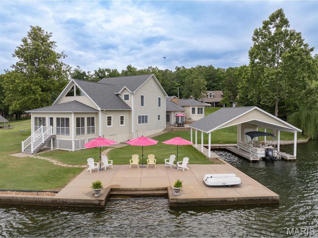 "THE Lake House" is beautifully positioned in the heart of desirable Lake Perry,  with secluded outdoor entertaining spaces and generously scaled interiors complemented by timeless architecture. Gracious gathering rooms are accented by intricate millwork, expansive vaulted ceilings and a multitude of windows that fill the home with natural light. This well-maintained, modern home (built in 2007) offers comfortable living with tile flooring throughout the entire main level. The spacious family room with one of the two floor to ceiling stone recirculating fireplaces flows seamlessly into the kitchen and dining area, creating an open-concept layout perfect for everyday living and entertaining. Step directly from the family room onto the covered back patio, ideal for relaxing or hosting guests. On the main level of the primary residence, you will also find a welcoming office, full bath and convenient large main-floor laundry/mudroom. Timeless, sophisticated, and undeniably captivating, it is a rare architectural treasure, designed to capture both sunlight and serenity that sets a tone of quiet grandeur and gracious hospitality. ++++++++ Upstairs, the primary bedroom and 3 additional bedrooms are generously proportioned and provides exceptional privacy for guests. The main residence offers a rare balance of architectural significance and everyday livability. Beyond, a tranquil screened porch facing the lake offers a peaceful retreat for reading, reflection, or simply watching the seasons change.  This effortless connection to outdoor entertainment invites memorable dinners and celebrations both large and small.  Here, grand entertaining and quiet mornings, historic character and modern luxury, all exist in perfect harmony. ++++++ There is much more: Cruise into the ample parking pad or pull into the newer attached garage.  Meander over to the inviting patio and maybe put your feet in the water or take steps down to your kayak or canoe for a leisurely early morning ride.  If you like, find your boat in the covered newer doublewide dock and away you go. +++++++ There is even more:  Completely separate but connected by the common covered patio is a guest cottage that consists of a massive living room featuring a stunning wood vaulted ceiling and floor to ceiling stone recirculating fireplace with a sizeable bay window area that accommodates the dining table. There is also a full bath and tucked in refrigerator.  +++++++When you saunter up a few stairs you pass through the perfect place for your own art gallery. Exit the door to yet another vast patio with permanent benches.  Once you pass through your artwork you will come to an over 250 sq. ft multipurpose room featuring 2 walls of windows.  This room has unlimited uses. It could be for more art, work out, second living room, study, library, craft or sewing room, card room, or other use. The 5th bedroom is located past the amazing room. +++++++This chateau is a one of a kind that has all of the amenities, charm, comfort, privacy, breathtaking views of nature and the lake. Make it your home.