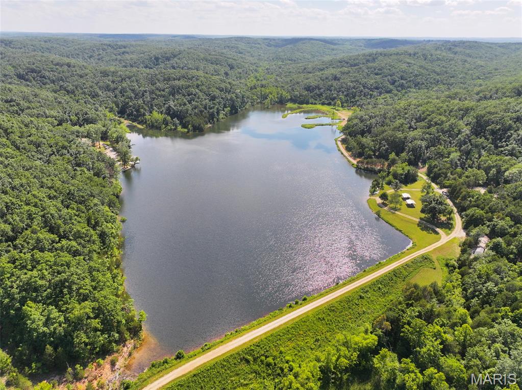 Located in the Hidden Valley community off Holmes Road in southern Ste. Genevieve County, this approximately 10 +/- acre recreational property offers a unique opportunity to own wooded acreage along a shared private lake. Access is provided by a rocked driveway that leads to the property, which is situated adjacent to the community pavilion and boat launch area, making it convenient to enjoy everything the lake has to offer. The property is entirely wooded, providing a natural setting with opportunities to enjoy the outdoors in every season. The rolling terrain offers several locations that could accommodate a cabin or camper site, subject to any applicable restrictions and approvals. Many of these locations overlook the lake, allowing owners to enjoy views of the water while surrounded by mature woodland. This property does not currently have electric service available, making it well suited for those seeking an off-grid recreational retreat. Whether you're considering a weekend cabin, a seasonal camper setup, or simply a place to escape the pace of everyday life, this tract offers a quiet setting where you can disconnect and spend time outdoors. Hidden Valley Lake encompasses approximately 22 acres and provides a variety of recreational opportunities for property owners. The lake is stocked for fishing and also offers space for swimming, kayaking, canoeing, and relaxing on the water. With no permanent homes surrounding the lake, the area maintains a peaceful atmosphere that is becoming increasingly difficult to find. Beyond the lake itself, the wooded acreage provides opportunities for hiking, wildlife observation, and exploring your own piece of southern Missouri. The combination of timber, lake frontage, and nearby common amenities creates a versatile recreational property that can be enjoyed throughout the year. The property's location in southern Ste. Genevieve County provides a balance of privacy while remaining within a reasonable drive of nearby communities for supplies and services. Whether you're looking for a place to gather with family and friends, spend weekends fishing, enjoy evenings around a campfire, or simply own acreage with lake access, this property offers a variety of recreational possibilities. Smaller lakefront tracts with acreage are becoming increasingly difficult to find, especially those offering privacy and access to a stocked private lake. If you've been searching for a recreational property where you can enjoy fishing, swimming, and the outdoors in a peaceful setting, this Hidden Valley property is worth a closer look.