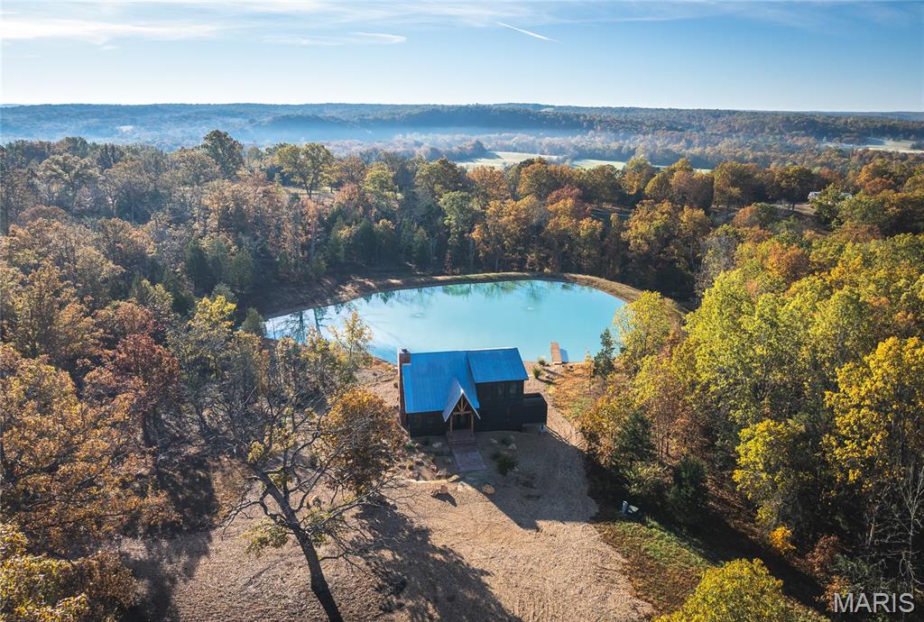 White Oak Luxury Cabin on the Meramec River – 47 Acres of Ozark Perfection! Welcome to White Oak Cabin, a luxurious retreat nestled on 44 acres of rolling hills covered in mature white oak timber and your very own 3 acres of private access to the crystal-clear Meramec River! This exceptional property offers three acres of private gravel bar, perfect for fishing, swimming, picnicking, and camping along one of Missouri’s most beautiful stretches of river, and is located five miles upstream from the nearest commercial float access point, making it one of the quietest, most unused portions of the river!  Attention all trout fishermen! World class trout fishing at Meramec Springs Park is less than 8 miles away! 
The 1,466 sq. ft. custom-built cabin showcases timeless craftsmanship with mortise and tenon timber frame construction, James Hardie fiber cement siding, and a metal roof designed to last a lifetime. Inside, no expense was spared — from the 3/4” white oak flooring and Cambria quartz countertops to the custom-built white oak kitchen cabinetry and reclaimed brick wood-burning fireplace, crafted from bricks salvaged from a historic St. Louis building. The main level offers an open-concept living space with stunning views and a king-sized primary suite with a luxurious full bath, providing both comfort and elegance. Upstairs, the 380 sq. ft. loft suite includes a full bath and panoramic views of the surrounding hills, while the 1,128 sq. ft. basement features two sleeping quarters, a half bath, 9-foot poured walls, and UTV parking with an overhead door for convenient access. Outside, the beauty continues with landscaped boulders and stepping stones, a fire pit overlooking the 1.5-acre pond, and an outdoor shower for rinsing off after river adventures. The pond is aerated, stocked with bass, and perfectly maintained — a serene centerpiece to the property. Modern comforts blend seamlessly with natural beauty, featuring geothermal HVAC, 1-gig fiber optic internet, and thoughtful touches throughout. The property is a haven for wildlife, serving as a sanctuary for deer, turkey, squirrel, and rabbit, with established trails for hiking, trail riding, and exploring. Whether you’re seeking a private getaway, a full-time residence, or an investment in Ozark luxury — White Oak Cabin on the Meramec River offers an unmatched combination of craftsmanship, comfort, and natural splendor.