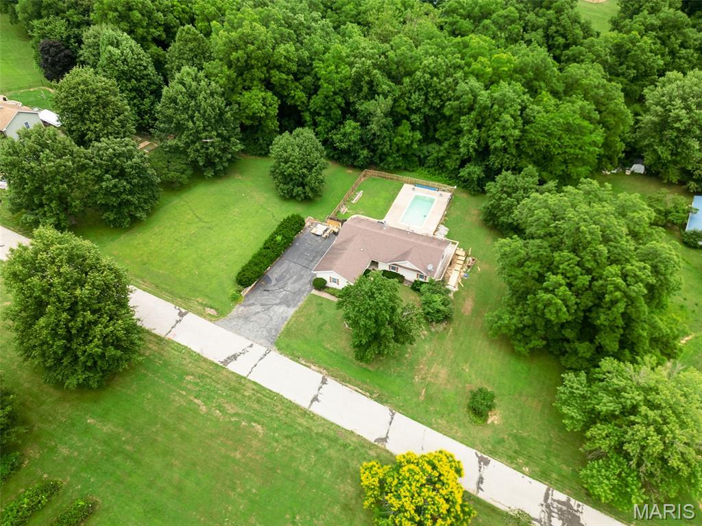 Did you ever think you could buy a walk out ranch with partially finished lower level, and your own private in ground pool on almost an acre lot for just $275,000? Well it is your lucky day, because THIS IS IT! This spacious ranch home offers hardwood floors throughout the large vaulted great room w/beautiful wood burning fireplace, as well as kitchen and dining area. Walk out back door to large wrap around deck, overlooking your beautiful pool, and private wooded lot. Such a great set up to entertain your friends and family! Lots of windows for so much natural light in this open floor plan home!  Stainless appliances in the kitchen w/dishwasher new 2025. Primary suite offers fan, walk in closet plus second closet and full bath w/shower. 2 additional bdrms and full bath on main level. Large recreation room plus another full bath in basement, plus additional finish work started in other areas, just waiting for your finishing touch! New HVAC system and hot water heater in 2025. Architectural shingle roof. 2 1/2 car garage. ALL this and more in .91 private acres w/lots of beautiful large trees! Some work needed on decking around pool area. Tons to offer with this great property!
