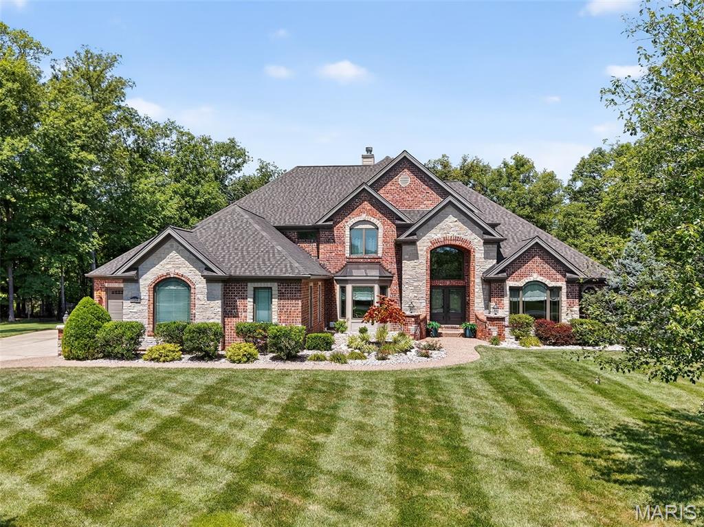 Discover refined living in this stunning 1.5-story home, nestled on 3 private, wooded acres in an exclusive Defiance neighborhood. With over 6,000 sq ft of luxury, this thoughtfully designed home impresses at every turn. The two-story great room features hardwood floors, soaring ceilings, and a cozy double-sided fireplace shared with the hearth room—perfect for taking in serene views of the backyard oasis. The chef’s kitchen boasts custom cabinetry, Quartz countertops, center island breakfast bar, built-in fridge, SS appliances, and double wall ovens. The spacious main-floor primary suite offers a tray ceiling, dual walk-in closets with custom shelving, and a spa-like ensuite with a soaking tub and oversized tile shower. Three upstairs bedrooms each enjoy private bath access. Additional highlights include a formal dining room, main-level office, and an enormous finished walk-out lower level with 9' pour, featuring a rec room, fireplace, wet bar, gym, and full bath. Step outside to your private retreat complete with a tranquil pool surrounded by nature. Two attached garages with space for five vehicles. New roof (2024), newer HVAC, and located in the sought-after Francis Howell School District—just minutes from I-64/364. A rare find—schedule your showing today!