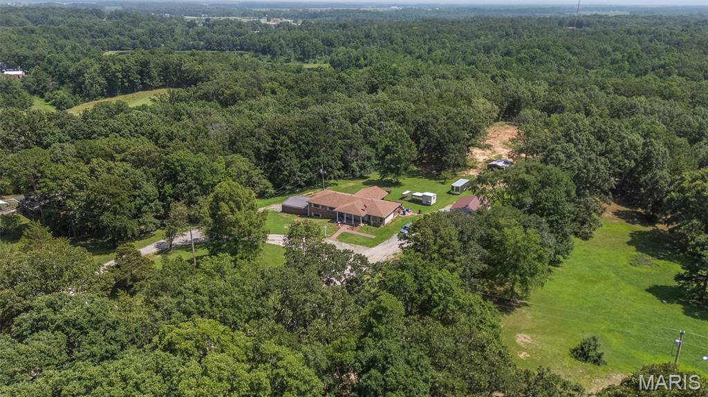 Discover the perfect blend of comfort, space, and privacy with this charming brick home nestled on over 5 acres of beautiful mixed cleared and wooded land. Whether you're looking for room to roam, space for hobbies, or peaceful country living, this property offers endless possibilities.
A welcoming covered front porch invites you inside, where you'll find new windows and updated flooring throughout most of the main level. The galley-style kitchen features a cozy eat-in dining area with direct access to the new partially covered back deck, perfect for enjoying your morning coffee, outdoor dining, or relaxing while overlooking the property.
Just off the kitchen, the spacious living room flows into a versatile space accented by a  bay window, ideal as a formal dining room, reading nook, home office, or additional sitting area. The primary suite offers a newly remodeled walk-in shower, while the additional bath on the main level includes a soaking tub. Downstairs, the walk-out basement expands your living space with a private bedroom, bathroom, comfortable living area, and a large storage room that also serves as a storm shelter.
Outside, you'll appreciate two detached shop buildings, providing ample room for equipment, vehicles, workshops, hobbies, or additional storage. With its combination of updates, functional layout, and scenic acreage, this property offers the ideal balance of country charm and everyday convenience.