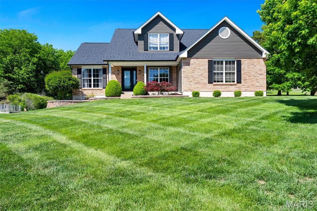 Welcome home to this sought-after 1.5-story gem nestled in the beautiful lake community of Bridgewater Estates with convenient access to I-44! From the moment you step inside, you’ll love the abundance of natural light pouring through the dramatic wall of windows in the spacious living room, highlighted by a cozy see-through fireplace shared with the charming breakfast room featuring a bay window. A separate formal dining room provides the perfect space for hosting holiday gatherings and entertaining guests in style.  
The deluxe kitchen is designed for both everyday living and entertaining, complete with stainless steel appliances, ample cabinetry, and beautiful hardwood and ceramic tile flooring throughout the main level. Convenient main-floor laundry adds to the home’s functionality. Retreat to the vaulted primary suite on the main level featuring gleaming hardwood floors, ceiling fan, and a luxurious primary bath with double sinks, separate tub, and shower. Upstairs offers a versatile loft area, two spacious bedrooms, and a full bath — perfect for family or guests. The partially finished lower level provides even more living space with a rec room, game room area, and bath, giving you endless possibilities for entertaining or relaxing. Step outside and fall in love with the gorgeous exterior setting featuring an expansive green lawn, lake views, a fully fenced backyard, and an inviting 24x14 patio ideal for outdoor gatherings. Car enthusiasts and hobbyists will appreciate the attached oversized 2-car garage plus an additional oversized detached 2-car garage offering exceptional storage and workspace.
This beautiful home combines comfort, space, and scenic surroundings in one incredible package — a rare opportunity in highly desirable Bridgewater Estates!