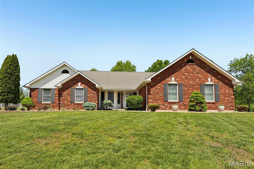 Every once in a while, a property comes along that feels less like a home… and more like the lifestyle people spend years hoping to find. Tucked gently atop 4.5+/- beautifully manicured acres with sweeping views of open farmland, this stunning brick residence offers the kind of peace, privacy, and flexibility that’s becoming increasingly rare to find — especially while still being conveniently positioned between Hwy 61 and Hwy 79 for an easy commute back toward the city.

From the moment you pull up the gravel drive, there’s an unmistakable sense of arrival. Mature landscaping, meticulously maintained grounds, and the stately brick veneer exterior immediately set the tone for what’s inside. Step through the front door and you’re welcomed into a warm, inviting living space filled with natural light pouring through Anderson windows and skylights above. Vaulted ceilings with a striking center beam create an open, airy feel, while the gas log fireplace anchors the room with the perfect touch of comfort and character.

The kitchen was designed for both gathering and functionality, featuring granite countertops, breakfast bar seating, walk-in pantry storage, stainless appliances, and seamless flow into the main living areas. Whether it’s slow mornings with coffee overlooking the countryside or hosting family and friends for the holidays, this home simply lives well. Vinyl plank flooring runs throughout much of the main level, blending durability with timeless style, while thoughtful details like solid wood core doors, attic fan ventilation, central vac, and main floor laundry with utility sink reflect the level of care poured into the property over the years.

The primary suite feels like its own private retreat, complete with pocket doors, walk-in closet, staging area, and an updated bath that creates a relaxing escape at the end of the day. Downstairs, the finished walkout lower level dramatically expands the usable living space with soaring ceilings, ceramic tile flooring, full bath, additional laundry area, workshop space, and a second gas fireplace that creates the perfect setting for entertaining, hobbies, extended stays, or multi-generational flexibility.

But what truly separates this property from almost anything else on the market is what waits outside.

Imagine evenings spent on the partially covered composite deck watching sunsets fall across rolling fields. Summer gatherings stretched across the massive patio space. Quiet mornings with nothing but the sounds of nature surrounding you. And for the buyer needing more than just a home — the detached pole barn/shop opens the door to endless opportunity. With concrete floors, oversized access doors, electric, water, insulated workspace potential, and air compressor setup already in place, it’s perfectly suited for a home business, hobbyist workspace, storage for toys and equipment, or simply the freedom to create something uniquely yours.

This isn’t just another rural listing. It’s the kind of property buyers wait years to see hit the market — a turnkey country estate that combines comfort, utility, craftsmanship, and lifestyle into one unforgettable setting.