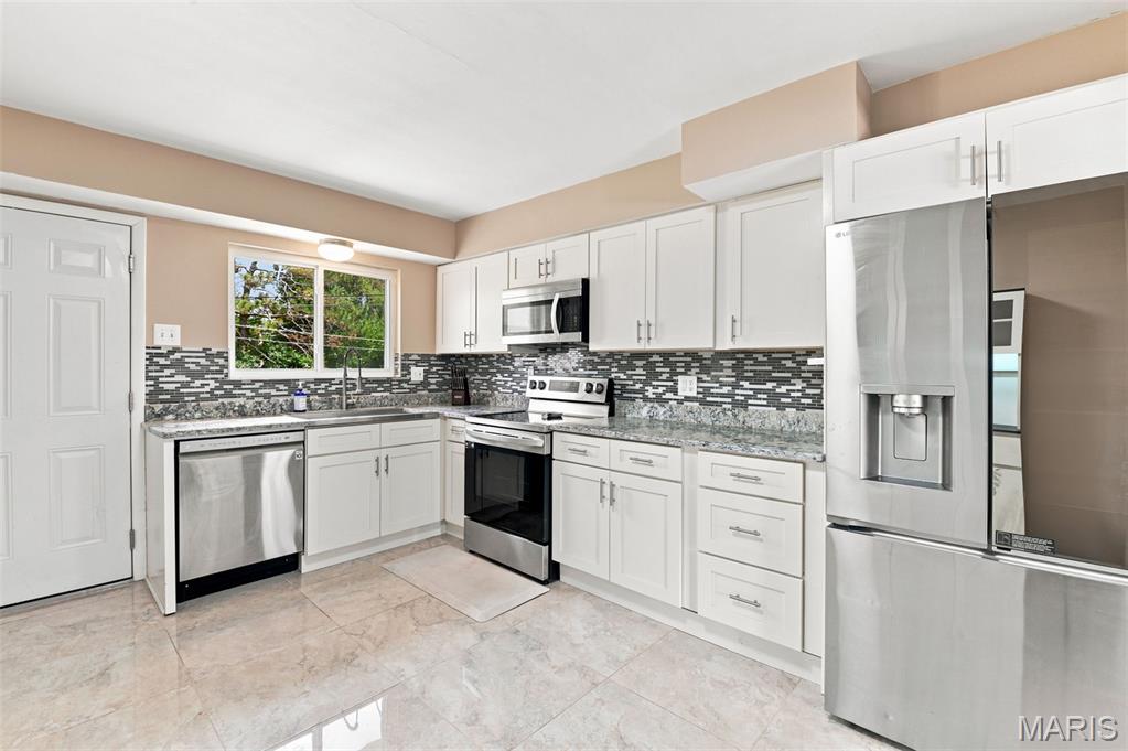 Do we have your attention now? Welcome home to this beautifully updated and move-in-ready ranch in the heart of University City - just minutes from Clayton! Walking distance to the golf course!  If you are searching for a home with modern updates and exceptional value, this one deserves a spot at the top of your list. From the moment you step inside, you'll appreciate the abundance of natural light, beautiful hardwood flooring, and thoughtful improvements throughout. Freshly painted and meticulously maintained, this beautiful home combines trendy upgrades on the surface, and important updates to the bones. The stunning kitchen has been completely refreshed and features granite countertops, stylish custom backsplash, and a full suite of LG Smart stainless-steel appliances that are less than two years old - and the matching fridge stays. The open and inviting layout offers comfortable living spaces perfect for everyday living and entertaining alike - including separate dining with stylish lighting.  The inviting hearth room or 4-season sunroom with updated fireplace create the perfect place to relax during cooler months, or additional year-round living space filled with natural light with a walk-out to the large back yard. The king-sized primary suite boasts double closets and has been enhanced with a fully renovated bathroom featuring a custom tiled shower with new plumbing. Additional updates throughout the home include new toilets, updated bathroom vanities, new windows and doors, and a newer AC system. Nearly all plumbing throughout the home has been replaced - no cast iron, providing peace of mind for years to come. One of the standout features is the expansive finished lower level offering approximately 1,300 square feet of additional living space. Whether you need a recreation room, media room, home office, workout area, hobby space, or all of the above, this versatile lower level provides endless possibilities. You'll also find a dedicated laundry area with Washer & Dryer included. Plus abundant storage space. Outside, you'll enjoy numerous exterior improvements including a roof that is less than two years old, professional chimney tuck-pointing, a new, expanded driveway with additional parking for 4. Convenient attached garage. The fenced, level backyard offers plenty of room for entertaining, gardening, pets, or outdoor recreation with a new covered patio. This gorgeous home recently passed the Municipal Occupancy, making it truly move-in ready. Location is everything, and this home delivers. Conveniently situated near Washington University, Forest Park, the Central West End, major highways, public transportation, shopping, dining, parks, and entertainment, you'll have easy access to everything St. Louis has to offer. With extensive updates, major systems already improved, additional finished living space, and an unbeatable University City location, this home offers exceptional value and is ready for its next chapter. Schedule your showing today before this opportunity is gone!