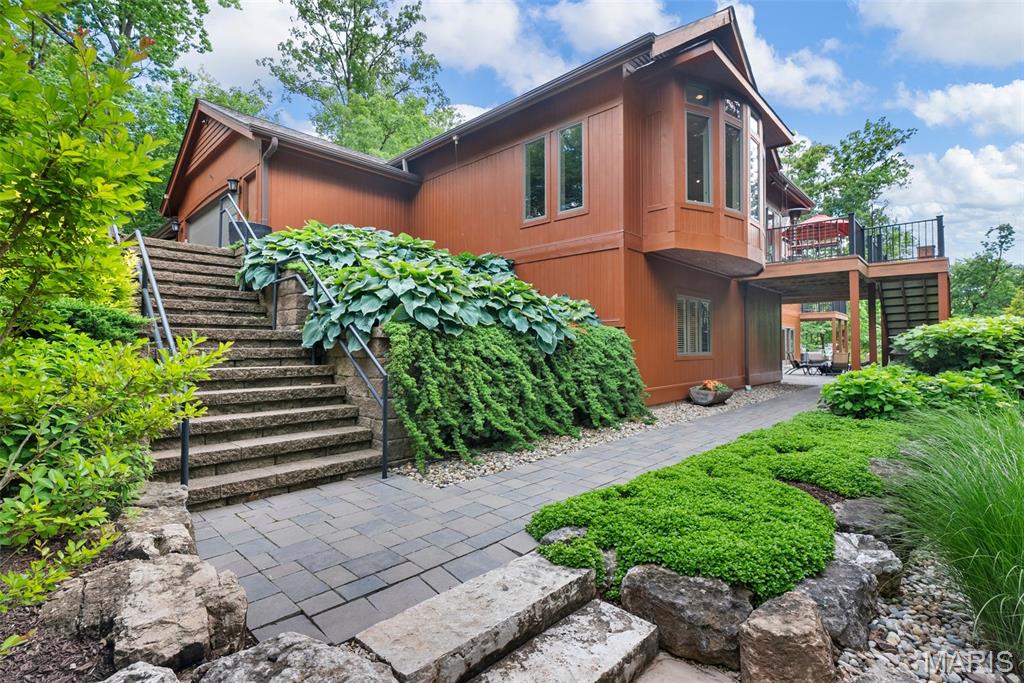 Step into serene, low-maintenance luxury with this beautifully landscaped property sitting on over an acre in the heart of Creve Coeur featuring a thoughtfully designed rock garden hardscape. Perfectly blending form and function, the rock garden adds striking visual appeal while offering a water-wise solution ideal for today's eco-conscious homeowner. Natural stone elements, strategically placed boulders and paved walkways create a calming, Zen-like outdoor retreat—ideal for relaxing or entertaining. Designed and remodeled by a general contractor for his personal residence, it features over 6,000 sq ft of refined living space, including vaulted ceilings, real maple hardwood floors, and custom millwork throughout. The gourmet kitchen boasts two expansive islands, granite countertops, and premium stainless appliances. The primary suite includes two walk-in closets and a spa-like bath, while each additional bedroom has its own en suite. Enjoy dedicated spaces for an office, home gym, ll family room and bar area and mother-in law quarters.  Walls of windows provide serene, wooded views, complemented by two private decks and a flagstone patio perfect for outdoor entertaining. Whether you're a gardening enthusiast or simply appreciate sustainable outdoor living, this unique feature enhances curb appeal and adds timeless value to the home. Secluded yet conveniently located near top schools, hospitals, and major highways—this is luxury living at its finest.