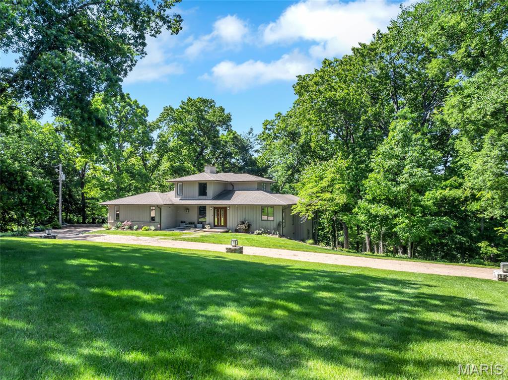 Unique one of a kind Rustic Contemporary home, tucked away on 5+acres in Wildwood providing extreme privacy. Thoughtfully remodeled blending organic textures with sleek modern design. This 1.5 sty has 4 bedrooms 3 & 1/2 baths. The entry  is bright and light with a wall of windows and dramatic custom glass staircase w/ stainless steel handrails. . Sunken living room w/gas fireplace looks out to the tranquil woods & fenced back yard complete with sprinkler system.   Gourmet kitchen is a showcase of craftsmanship, with Thermofoil soft close cabinets, Cambria quarz counters, double gas oven/range, SS vent hood, microwave drawer, built-in SS side by side refrigerator, Liebherr wine tower w/dual temp, Bosch dishwasher, Miele built-in coffee maker with plumbed in water line. The  pantry has custom shelving.  Open dining room features a wet bar/butlers pantry with Liebherr under counter wine refrigerator, sink and cabinets-perfect for entertaining. Main floor primary bedroom and luxurious bath with bidet. Walk-in organized closet with dressing area. The screened porch looks out to the trees and back yard and has stairs to the maintenance-free deck and Hot Tub that is included.. Upstairs the 2 bedrooms share a fabulous bath. As a bonus there is a  walk-in organized hall closet. The Lower level has bedroom 4  with a dressing room & large walk-in organized closet. Full bath #3 in the LL has beauitful tile and marble.  Family room with a Gas fireplace and a direct access door to the Hot Tub.  Additional enhancements include Spire natural gas service brought to the home for premium appliance performance.  Plus there are two exterior storage buildings (18 x14 and 19 x 9) offering exceptional utility without compromising the property’s aesthetic. If you are looking for privacy and elevated living, here is your modern sanctuary!