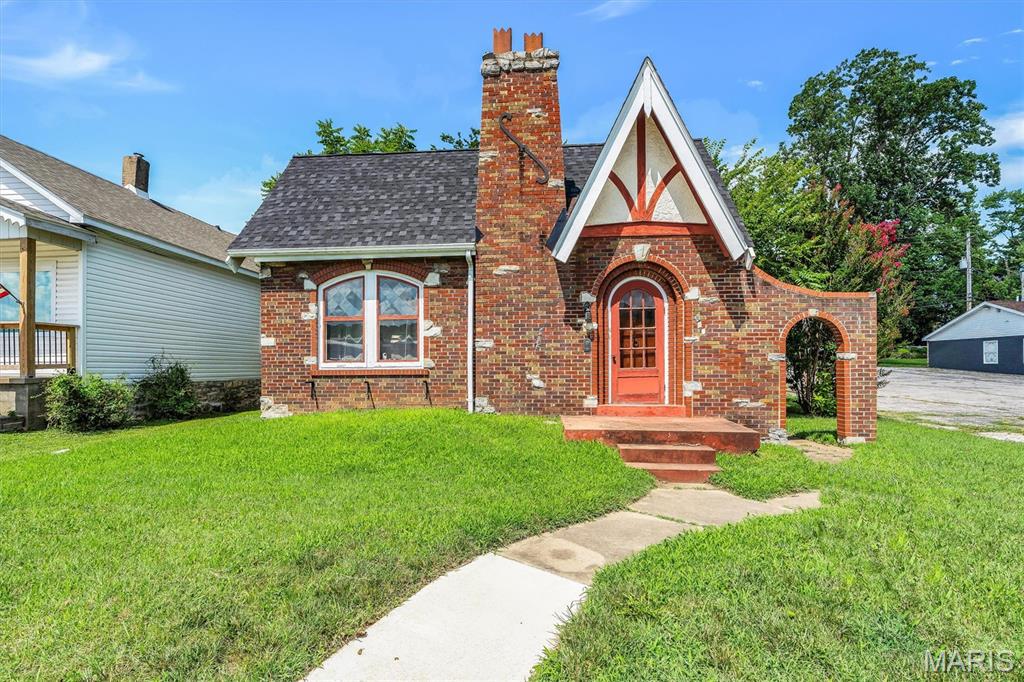 Timeless Tudor charm meets everyday comfort in this all-brick home in the heart of De Soto. Filled with character, this home features hardwood floors, soaring 10-foot ceilings in the living room, a fireplace, stained glass windows, arched doorways, stucco walls, and custom millwork. The spacious eat-in kitchen offers plenty of room for family meals and gatherings, while 9-foot ceilings throughout the remainder of the home enhance the open feel. Two main-floor bedrooms and a charming glass-enclosed porch provide flexible living space for a home office, sitting room, or a peaceful spot to enjoy your morning coffee. A roof installed just one year ago adds extra peace of mind. The basement offers ample storage, and the level backyard provides plenty of room for outdoor enjoyment. Conveniently located near shopping, schools, and dining, this unique property is zoned for residential or commercial use, offering a variety of possibilities. Ready for its next chapter!