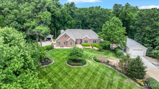 Welcome to this exceptional 4,500+ square foot custom-built ranch home perfectly situated on a park like 3-acre lot, offering an outstanding combination of luxury, comfort, and functionality. From the moment you arrive, the professional landscaping and inviting curb appeal set the tone for what awaits inside. Step through the front door to find tons of natural light, gleaming hardwood floors and soaring ceilings. The main level features large living room, formal dining room, hearth room w/wood burning fireplace & custom-built ins and separate breakfast room. Kitchen offers 42” custom cabinets w/ crown molding, quartz tops, prep island, sink in peninsula, custom stone backsplash, pantry cabinet & separate walk-in pantry. You will have a laundry room to be envied with tons of storage & custom laundry cabinets. The main-level primary suite serves as a private retreat with separate exit to the back deck, and a spa-inspired bath featuring separate vanities, a large walk-in shower w/ custom onyx surround, and a jetted soaking tub, water closet & large walk-in closet. Upstairs, you'll find a versatile bonus room that can accommodate a variety of needs with separate heating & cooling. The walk-out lower level expands the living space with an additional family room, recreation room, a safe room, and tons of storage & second ensuite with separate attached living space, full bath & large walk-in closet.  Outside, enjoy private, peaceful country views from the deck overlooking the expansive backyard. Adding tremendous value and versatility is the newer 50' x 24' outbuilding, providing ample space for equipment, hobbies, vehicles, workshop use, or additional storage. Outbuilding features concrete floors, electric, propane heat, foam insulation walls & ceilings, 10’ insulated overhead door, extra parking pad on the outside. This home also has a whole house Generac Generator, supplemental wood heat w/water furnace, an EV charger in the attached garage & all interior walls are insulated. Roof is only 1 year old. Water heater is BRAND NEW. Tranquility meets quality here in this one-of-a-kind home.