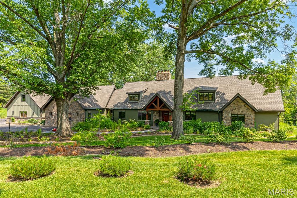 An impressive brick, stucco & cedar elevation defines the rustic architecture of this spectacular 7199 sf 1.5 Sty. Open floor plan features soaring ceilings, timber beams & oak hardwoods. Vaulted living room with stone accent wall with fireplace adjoins formal dining room & family room with expansive windows that offer sweeping views of the natural surroundings. Exceptionally large kitchen with glazed cabinetry, quartzite countertops, premium appliances, center island, butler’s pantry & fireplace opens to screened porch. 4 Additional bedrooms, 1 with ensuite bath & 2 with Jack n’ Jill bath, hall full bath, private study & bonus room complete the main floor living quarters. Oak staircase accesses primary bedroom suite with luxury bath with freestanding tub. Lower Level includes recreation room, 6th bedroom & full bath. Situated on a wooded 3-acre lot adjacent to Queeny Park with 2 patios & 4-car garage with carriage apartment plus an additional building with workshop & 2 horse stalls.