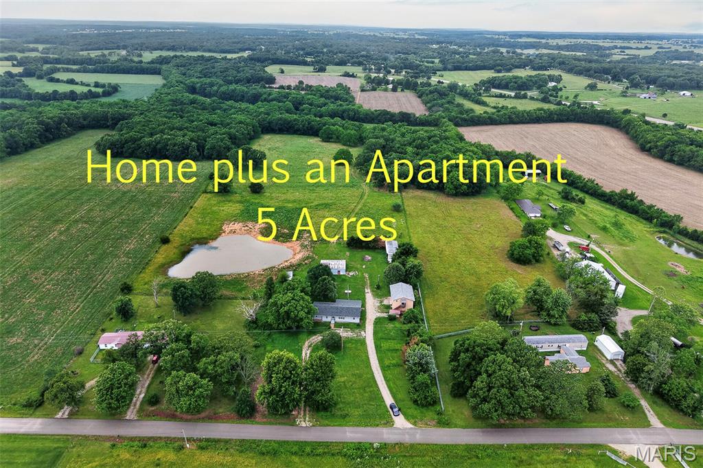 ONE OF A KIND! You will love the country setting with paved road frontage. This FIXER-UPPER!! Offers TWO homes on 5 acres. The main home is over 1,600 sq ft and has new siding and a brand-new roof.  New flooring throughout the main house will also be included. (ask your agent for details) Then you will have an open canvas to complete the extras you choose. Bring your creativity and make this home yours!! Additionally, there is a cute and practical apartment about 1,008 sq ft that includes a 2-car garage below and also a carport. The setting is nice & located a couple of miles from the city limits. It also includes an old barn and a storage shed, and a BEAUTIFUL large pond, and it will be surveyed! Make this property yours, rent the apartment for extra income, or easily accommodate two separate living spaces!