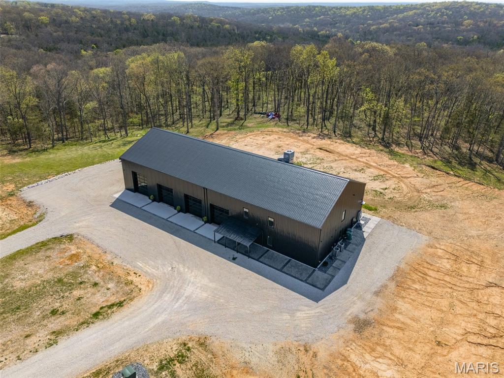 Experience the ultimate blend of modern luxury and private country living with this extraordinary new construction barndominium, set on an impressive 96 acres of rolling woods, open ground, and scenic creek views. This one-of-a-kind property delivers bold architecture, high-end finishes, and exceptional craftsmanship in every detail—creating a true retreat designed for both everyday living and unforgettable entertaining.
Inside, the open-concept design showcases soaring ceilings and heated concrete floors throughout. The designer’s chef’s kitchen is a statement space, featuring custom cabinetry, stamped concrete countertops, and a spacious walk-in pantry. The great room is anchored by a striking concrete feature wall with an electric fireplace, seamlessly flowing into the dining area and a large custom bar—perfect for hosting gatherings of any size.
The primary suite offers a peaceful escape with a walk-in closet and a spa-like bathroom complete with a soaking tub and oversized walk-in shower. A second bedroom, full bath, and laundry room completes the main level.
Upstairs, enjoy a versatile loft living area, third bedroom, additional sleeping room, extra storage, and a unique slide feature that adds both fun and character to the home.
The heated and cooled four-bay garage—including a 14-foot door—provides ample space for trucks, recreational vehicles, boats, and equipment.
Beyond the home, the land truly sets this property apart. The 96 acres offer a rare combination of mature timber, open fields, and a tranquil creek, creating the perfect setting for outdoor recreation and entertainment. Explore the private acreage ideal for ATV riding, hiking, or horseback use. Enjoy hunting opportunities with abundant wildlife or create your own outdoor oasis with space for firepits, shooting areas, camping sites, or future cabins.
Whether you envision weekend retreats, large family gatherings, or a private getaway built for adventure, this property delivers unmatched versatility. The mix of wooded privacy and open terrain also presents incredible potential for investors, developers, or those looking to establish a multi-home family compound, with the possibility to subdivide.