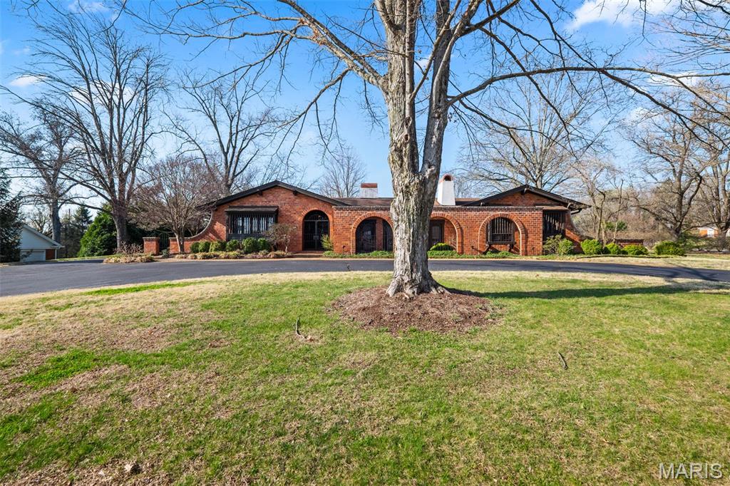 Set on 1.11 acres in Town and Country, this architecturally distinctive Higginbotham built estate offers timeless character, impressive scale, and a rare opportunity to create something truly special. The property features a pool, expansive grounds, and a Spanish-style courtyard, with wrought iron gates and terra cotta tiles, that sets it apart. Arched entryways and the gated courtyard create a welcoming first impression. Inside, hardwood floors, ceiling beams, and custom millwork add warmth and character. The grand living room features vaulted ceilings, a statement fireplace, and walls of windows and French doors for abundant natural light. Multiple living and entertaining areas include a formal dining room, expansive great room, and a spacious kitchen ready for reimagining. Architectural details such as arched passages and custom built-ins provide a strong foundation for renovation. The primary suite offers generous space, a walk-in closet, and a large bath footprint. Additional bedrooms are well-sized with hardwood flooring. The walk-out lower level includes a kitchenette, direct outdoor access, and extensive storage—ideal for guest quarters or additional living space. Additional highlights include an oversized 3-car garage and ample parking. A covered patio/sunroom overlooks the pool and backyard. Conveniently located adjacent to Bellerive Country Club. Home is to be conveyed "as is."