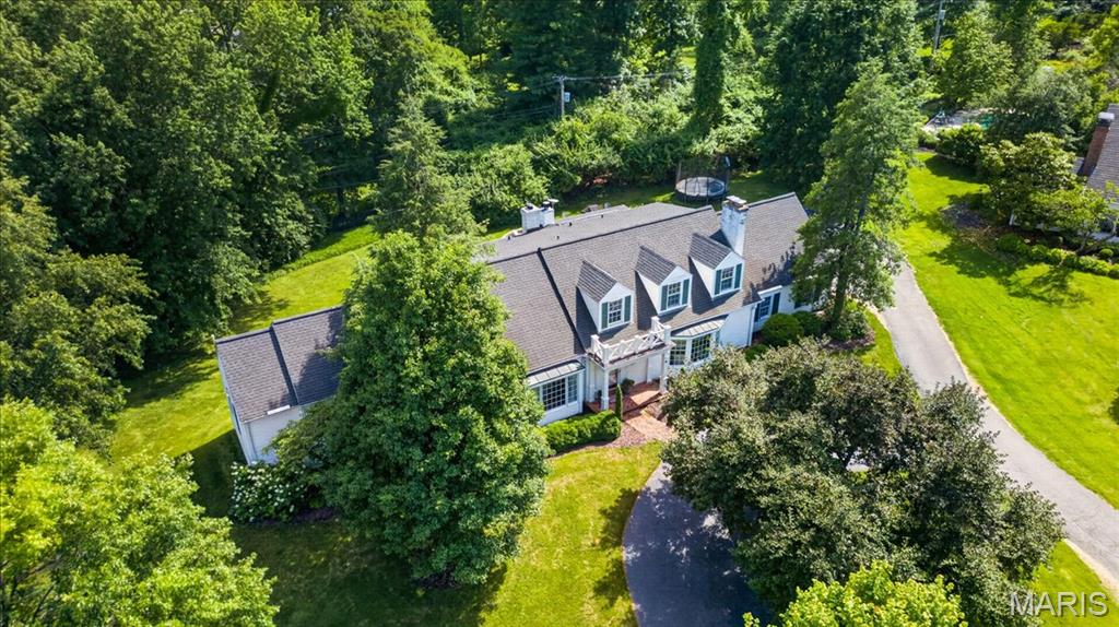 At the end of a quiet cul-de-sac in the heart of Ladue, this is the kind of home that naturally becomes the gathering place. Guests linger a little longer after dinner, and summer evenings naturally end around the fire pit. Designed with an exceptionally functional floor plan, the sprawling main floor primary suite feels like its own private wing, complete with a generous walk-in closet and spacious bath. Upstairs, three oversized bedrooms are complemented by two bonus rooms, offering endless flexibility for work, play, hobbies, or guests. The finished lower level adds an entirely new dimension to the home, offering substantial additional living space complete with a full bath, refrigerated wine cellar, private office or sleeping area, and additional recreation space. Surrounded by mature trees, the backyard is both private and peaceful, a setting equally suited for entertaining under the stars, quiet mornings with coffee, or creating the resort-style retreat you've always imagined. With ample room for a pool and outdoor living spaces, the possibilities are endless. Close to everything, yet tucked away from it all, this coveted Ladue location is just minutes from top-rated schools, country clubs, shopping, and dining offering the rare combination of convenience, privacy, and space.