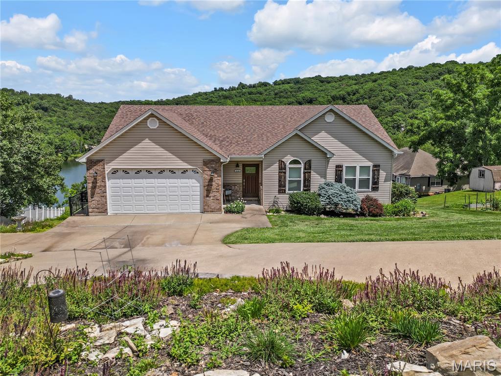 Wake up to breathtaking lake views in this beautifully maintained 3-bedroom home overlooking a private 12-acre lake. From the gorgeous landscaping to the updated wraparound deck, this property is designed to help you relax and enjoy the scenery. Inside, you'll find a beautifully updated kitchen and a separate dining room that walks out onto the deck, making indoor and outdoor entertaining a breeze. The cozy living room features a vaulted ceiling and fireplace, creating the perfect space to unwind while taking in the lake views. The main level offers a spacious primary suite with wonderful lake views, a walk-in closet, and a private bathroom, along with two additional bedrooms, main-level laundry, and an attached two-car garage. The lower level provides even more living space with a large family room that walks out onto a covered patio, a fourth bedroom, an additional office or sleeping room, another full bathroom, and a large unfinished storage area. 

An added bonus is the included second open lot, expanding the property to approximately 0.65 acres and providing extra yard space for outdoor activities, gardening, or simply enjoying the beautifully landscaped setting and lake views. 

Beyond the home, the subdivision's private 12-acre lake offers fishing, boating, and swimming opportunities just moments from your door. The common area also features a playground and BBQ pavilion, perfect for picnics, family gatherings, and making memories with friends and neighbors. Whether you're searching for a full-time residence or the perfect weekend escape, this lake-view home offers the best of comfort, recreation, and peaceful living.