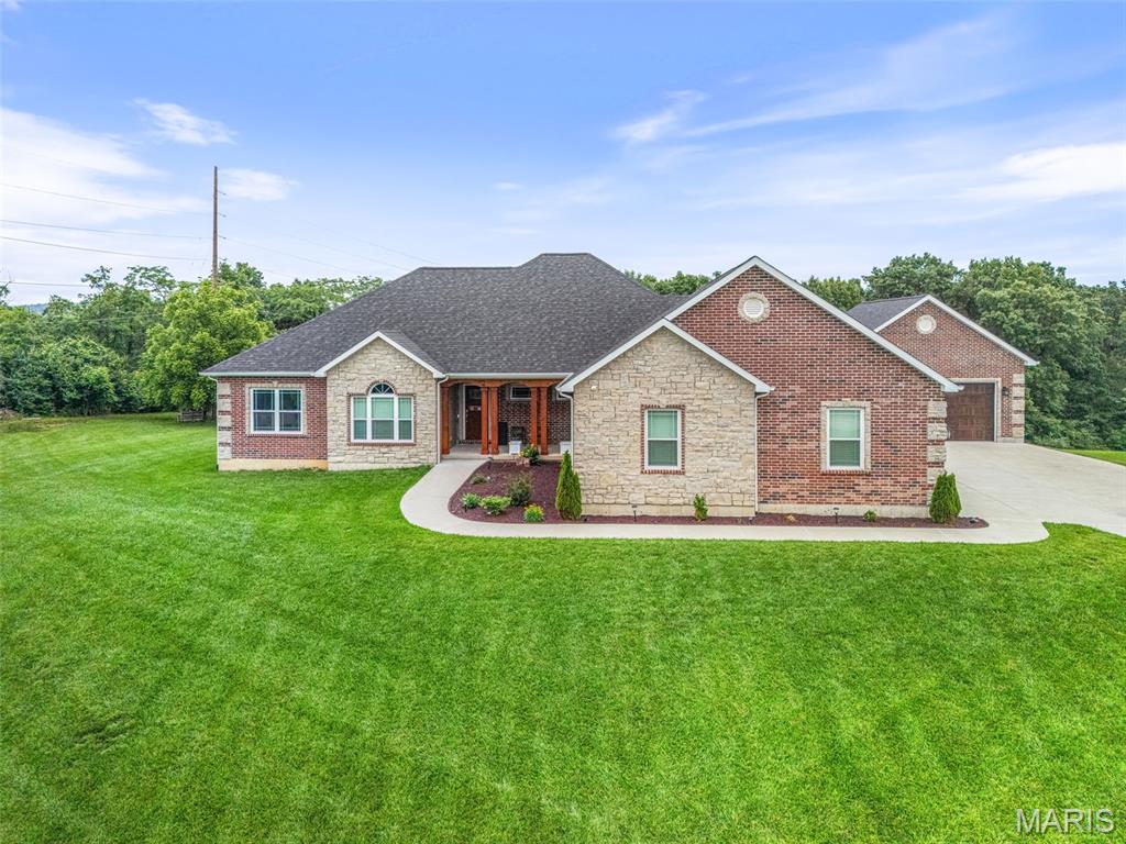 SERENE SETTING WITH GORGEOUS DREAM HOME!  Custom ranch home situated on 2.19 picturesque acres, offering exceptional space, style, and functionality. This 5-bedroom, 3.5-bath residence features a desirable divided floor plan and 10-foot ceilings throughout the main level, creating an open and airy feel.  The spacious great room is highlighted by a stone gas fireplace, coffered ceiling, and elegant crown molding, with direct access to a covered porch—perfect for relaxing or entertaining. The well-appointed kitchen includes granite countertops, a center island with breakfast bar, stainless appliances, and a walk-in pantry, ideal for both everyday living and hosting.  The main floor also offers a convenient laundry room. The finished walkout basement expands the living space with a kitchenette featuring granite countertops and stainless appliances, and opens to a huge concrete patio for outdoor enjoyment.  Lower level is complete with family room with fireplace, bedroom, full bath and still plenty of storage.  Car enthusiasts and hobbyists will appreciate the 3-car attached garage plus an additional 2-car detached garage, offering ample storage and workspace.  And don't miss the RV/electric car plug-in at the main garage.  Attentation has been paid to every detail so don't miss out on this incredible home!  NOTHING ELSE LIKE IT!