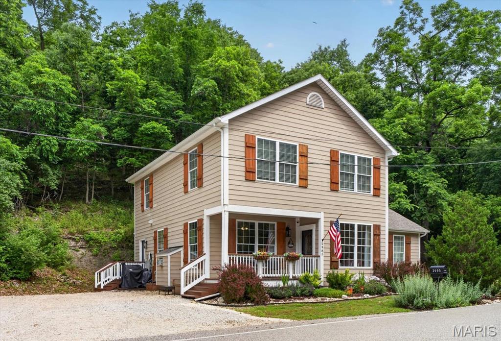 Country living in Wildwood! Charming, CUSTOM 1.5 story home, tucked away against Rockwood’s Reservation ground, on 1.35+/- level/sloping acres providing peace & tranquility. 2,322+/- SqFt, 3 bedroom, 3 full bath home. 8 1/2” Job-finished wood flooring throughout most of main level. Covered front porch & entry foyer greets you as you step inside. Living/dining room combo features a gas fireplace, recessed lighting, breakfast bar to Kitchen & walls of windows allowing plenty of natural light. Deer regularly wander across the hill behind the house, and watching the wildlife from the windows never gets old. Kitchen flaunts custom cabinetry, granite counters, tile backsplash, stainless steel appliances, pantry laundry closet (stackable only) & walk-out to side porch. Main level primary suite boasts 12’+/- vaulted ceiling and updated bath with double sink vanity w/granite countertop, custom shower, Jacuzzi tub and large picture window with the seclusion of natural rock cliffside. Completing the main level living space is a hall full bathroom. Upper level extends living quarters with 2 additional bedrooms with carpet, walk-in closets & share hall full bath. Outside, you will enjoy an AWESOME level, front/side yard with a wood deck & gravel parking lot. NEW roof/gutters (2025) & NEW septic tank pump (2026). Within the Rockwood School District, easy access to Highway 100/Manchester Road & minutes to Wildwood Town Center, shopping, parks, dining & amenities. MUST SEE! **NOT IN FLOOD PLAIN**