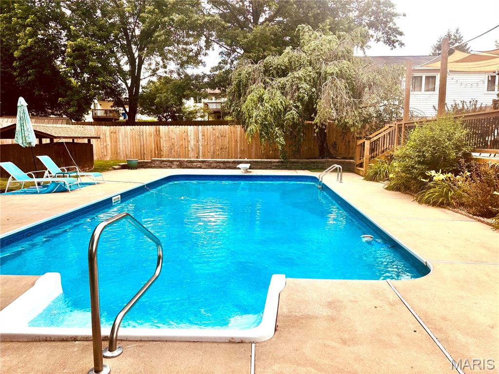 Vacation at home in this beautifully updated walkout ranch featuring your own private backyard oasis! The centerpiece of the outdoor space is a sparkling 20x40 saltwater pool, perfect for summer fun and relaxation. The pool liner was replaced approximately 10 years ago, and the refurbished pool pump has been serviced by St. Charles Pool Company.

The backyard is designed for entertaining with a huge two-tiered deck replaced in 2018, a shaded back porch, beautiful landscaping, a large storage shed for pool supplies, and a wood privacy fence replaced in 2023. An additional parking pad provides space for a third vehicle.
Inside, you’ll love the inviting living room featuring a bay window, gas fireplace, and tile (plank look) flooring. The  bright updated kitchen with a skylight