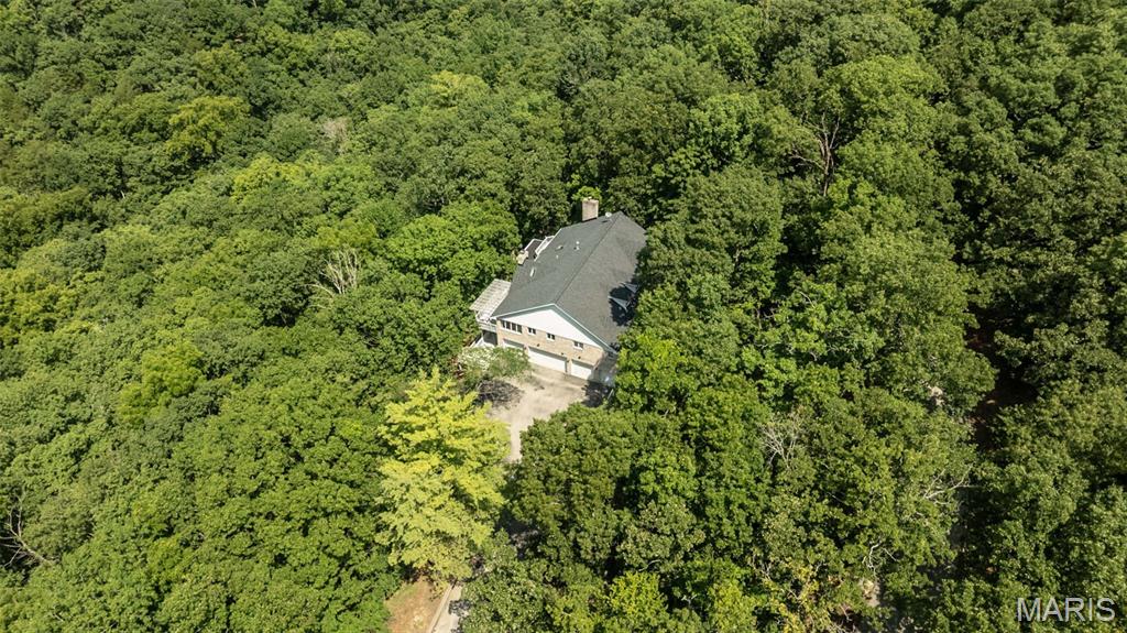 Tucked away on 4 private wooded acres in the highly acclaimed Rockwood School District, this one-of-a-kind property offers breathtaking western sunset views over the Eureka Valley and an incredible opportunity to create your dream home in a setting that's nearly impossible to find. With over 3,200 square feet, 4 bedrooms, 3.5 baths, FIVE CAR GARAGE, and exceptional architectural character, this custom home is ready for its next chapter.

Step inside to soaring vaulted ceilings, skylights, expansive windows, a dramatic floor-to-ceiling stone fireplace, and generous living spaces designed for gathering. The updated kitchen features granite countertops, newer stainless steel appliances—including a convection oven—and opens seamlessly to the heart of the home. The renovated primary bath, oversized custom walk-in closet, newer carpet in three bedrooms, 2018 HVAC, and roof replaced approximately three years ago provide an outstanding head start, leaving the next owner free to personalize the remaining spaces to their own style.

The expansive walkout lower level with a second fireplace and full bath has been professionally cleaned and sanitized, offering endless possibilities for additional living space, recreation, or entertaining.

Outside, four decks, two peaceful koi ponds, and nothing but mature trees create a true private retreat. And for car enthusiasts, hobbyists, or anyone needing extraordinary storage, the incredible 5-car garage offers space for multiple vehicles, a workshop, or your favorite toys.

If you've been searching for privacy, acreage, and the chance to make a remarkable home your own, this is an opportunity you won't want to miss.

Property is being sold As-Is. Seller will not may for or make any inspections or repairs. Seller is offering 1 year Choice Home Warranty.