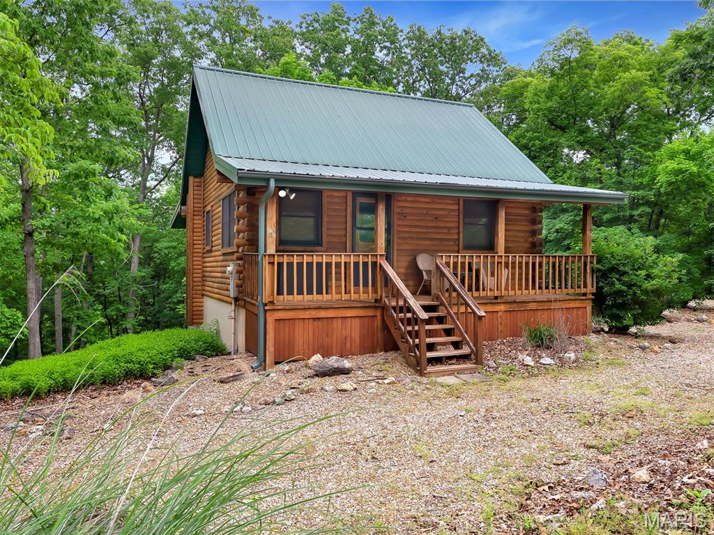 Escape to your own private woodland retreat tucked away on 1.6 scenic acres in the highly sought-after Anthony’s Mill community, with an additional 1.1-acre lot (#132) included in the sale for even more room to roam and enjoy nature. Surrounded by peaceful wooded views, this inviting 2 bed, 2 bath getaway blends rustic charm with cozy comfort and will be sold mostly furnished, making it easy to settle in and start enjoying immediately.

Inside, warm woodwork throughout creates the perfect cabin-inspired atmosphere, while vaulted ceilings and an open-concept layout fill the home with character and an airy feel. The kitchen features stainless steel appliances and flows effortlessly into the main living space, ideal for gathering after a day outdoors. The main floor offers a comfortable primary bedroom, full bath, and inviting living area, while the upper-level screened-in porch feels like a peaceful treehouse escape — the perfect spot for morning coffee or unwinding among the trees. Upstairs, the loft-style bedroom provides a cozy retreat for guests or additional sleeping space.

The finished walkout basement adds even more room to relax with a spacious family room, full bathroom, and laundry area. Outside, a storage shed offers added convenience, while the surrounding acreage creates a sense of privacy and serenity rarely found. A dedicated firepit area creates the perfect setting for cozy evenings under the stars, gathering with family and friends, and making lasting memories surrounded by nature. As part of Anthony’s Mill, enjoy access to incredible resort-style amenities including the lake, pool, tennis courts, volleyball court, and picnic areas. Whether you’re searching for a weekend escape, full-time residence, or turnkey retreat, this Bourbon property offers the perfect blend of nature, comfort, and community.